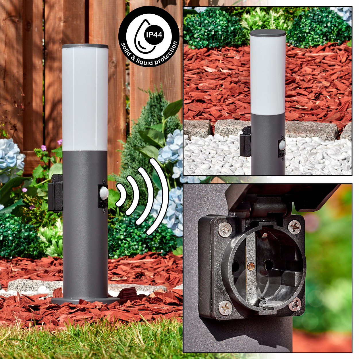 Eine graue Außenlampe mit weißem Oberteil. Sie hat einen Sensor und eine Steckdose. Die Lampe steht in einem Gartenbeet mit Holzschnitzeln.