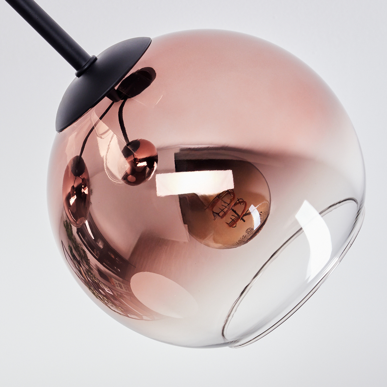 Moderne Leuchte. Eine klare Glaskugel mit rosafarbenem Oberteil, umschließt eine Glühbirne. Schwarzer Metallstiel und dekorative Elemente.