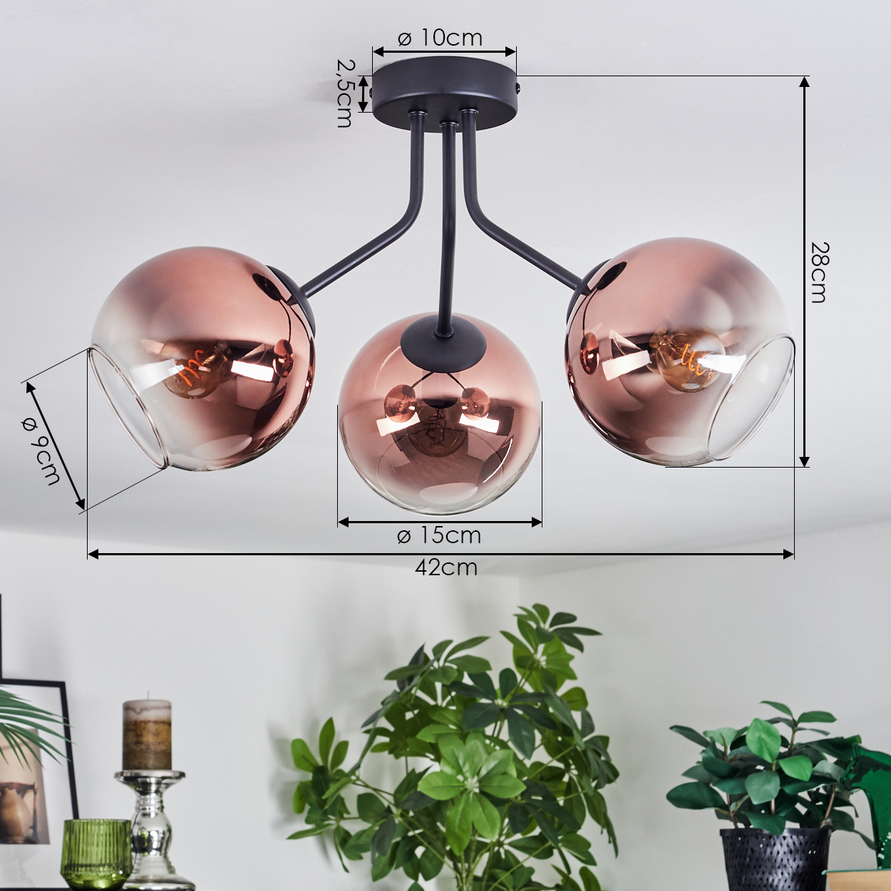 Eine moderne Deckenlampe mit drei kugelförmigen Schirmen. Die Schirme sind kupferfarben. Der Hintergrund zeigt Pflanzen und Möbel.