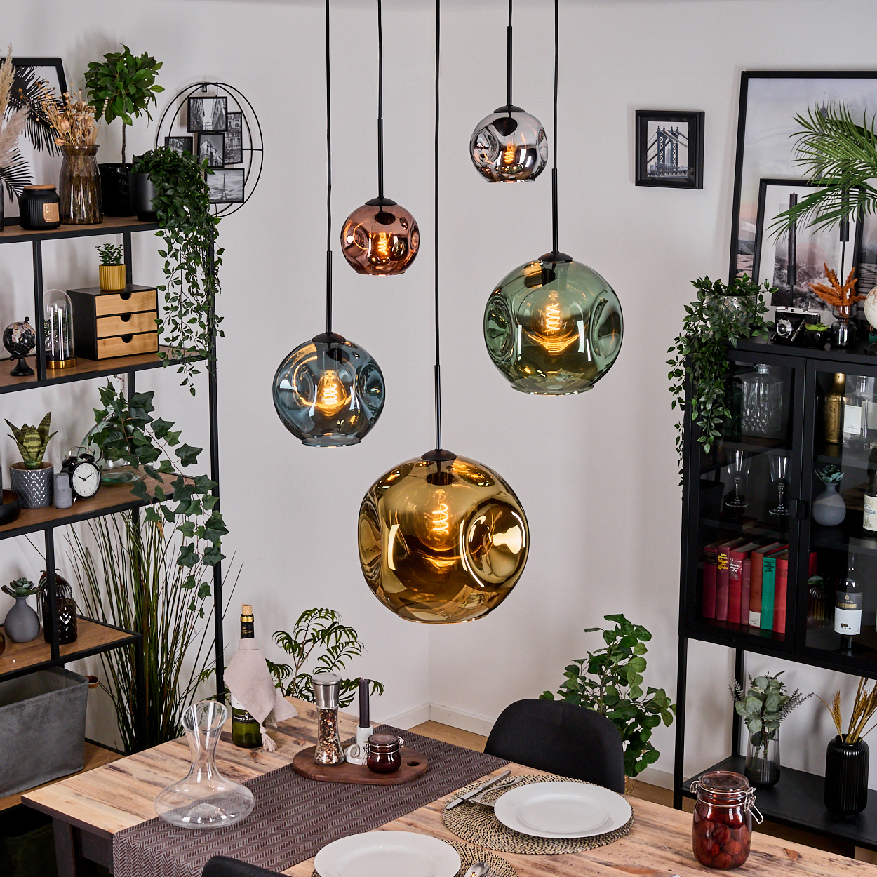 Esszimmer mit Holztisch, dekorativen Lichtern und Regalen. Pflanzen und Dekorationsartikel schaffen eine gemütliche Atmosphäre.