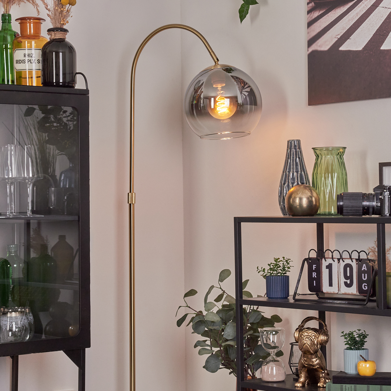 Ein Raum mit Lampe, Regalen und Dekorationsartikeln. Eine Glaslampe mit eingeschalteter Glühbirne steht im Mittelpunkt.