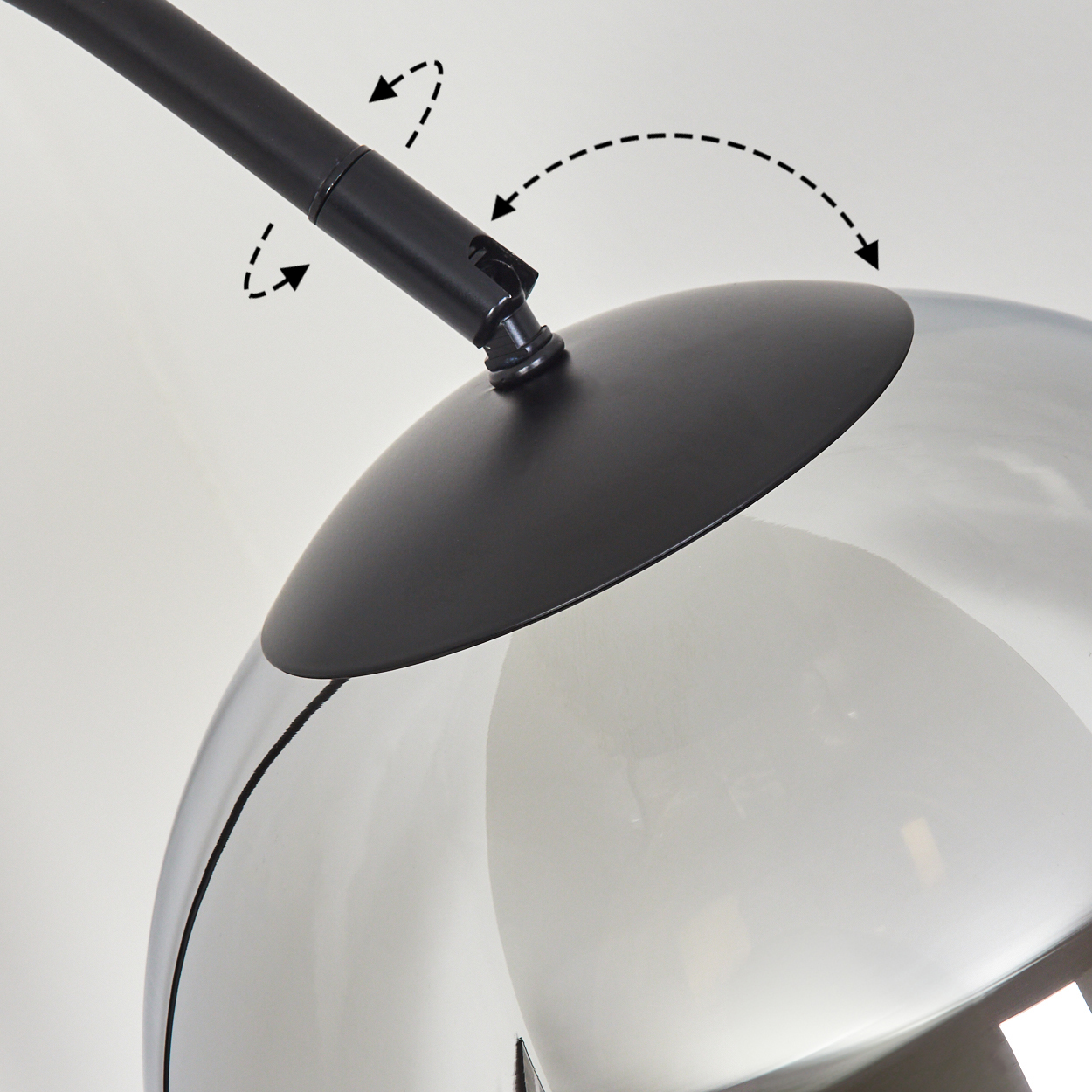 Eine moderne Lampe mit schwarzem Arm und Glasschirm. Der Schirm ist reflektierend und der Arm ist verstellbar.