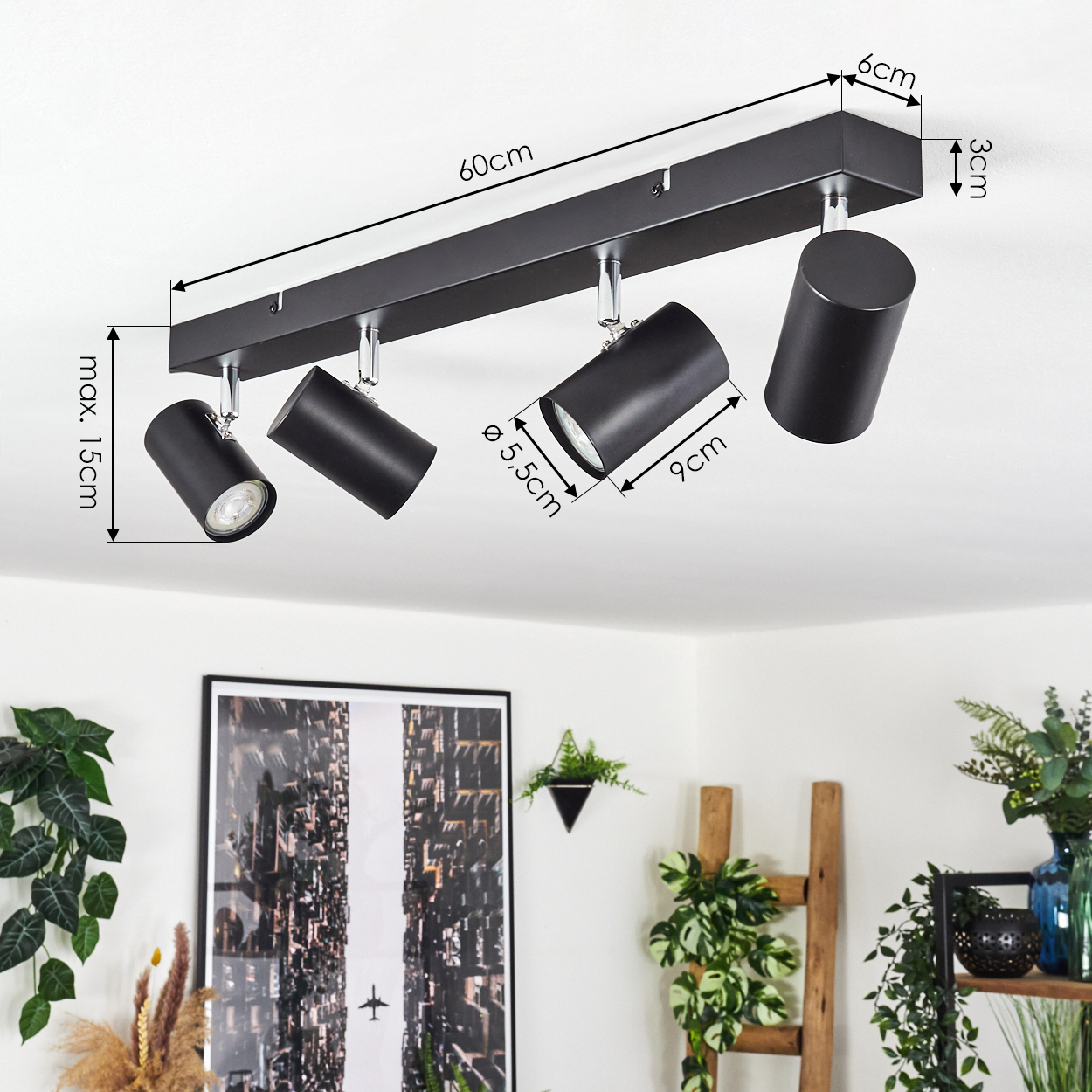 Schwarzer Deckenstrahler mit 4 verstellbaren Lampen, Maße angegeben. Pflanzen und ein Bild an der Wand im Hintergrund.