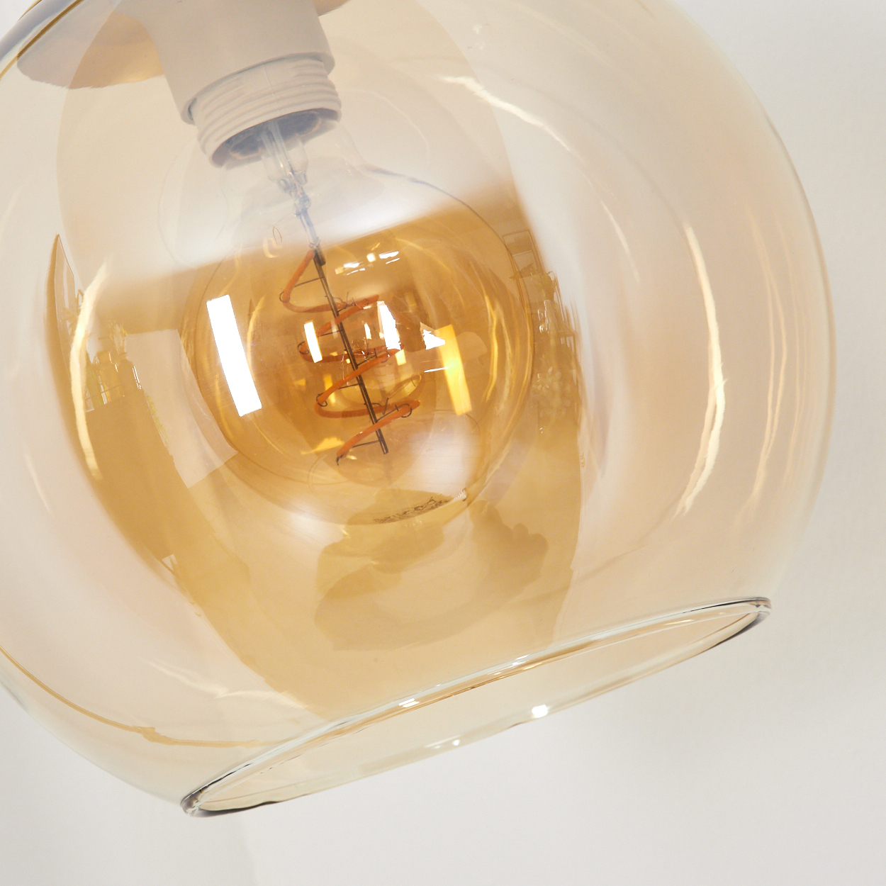 Nahaufnahme einer Glaskugel-Leuchte. In dem bernsteinfarbenen Glas befindet sich eine Glühbirne.