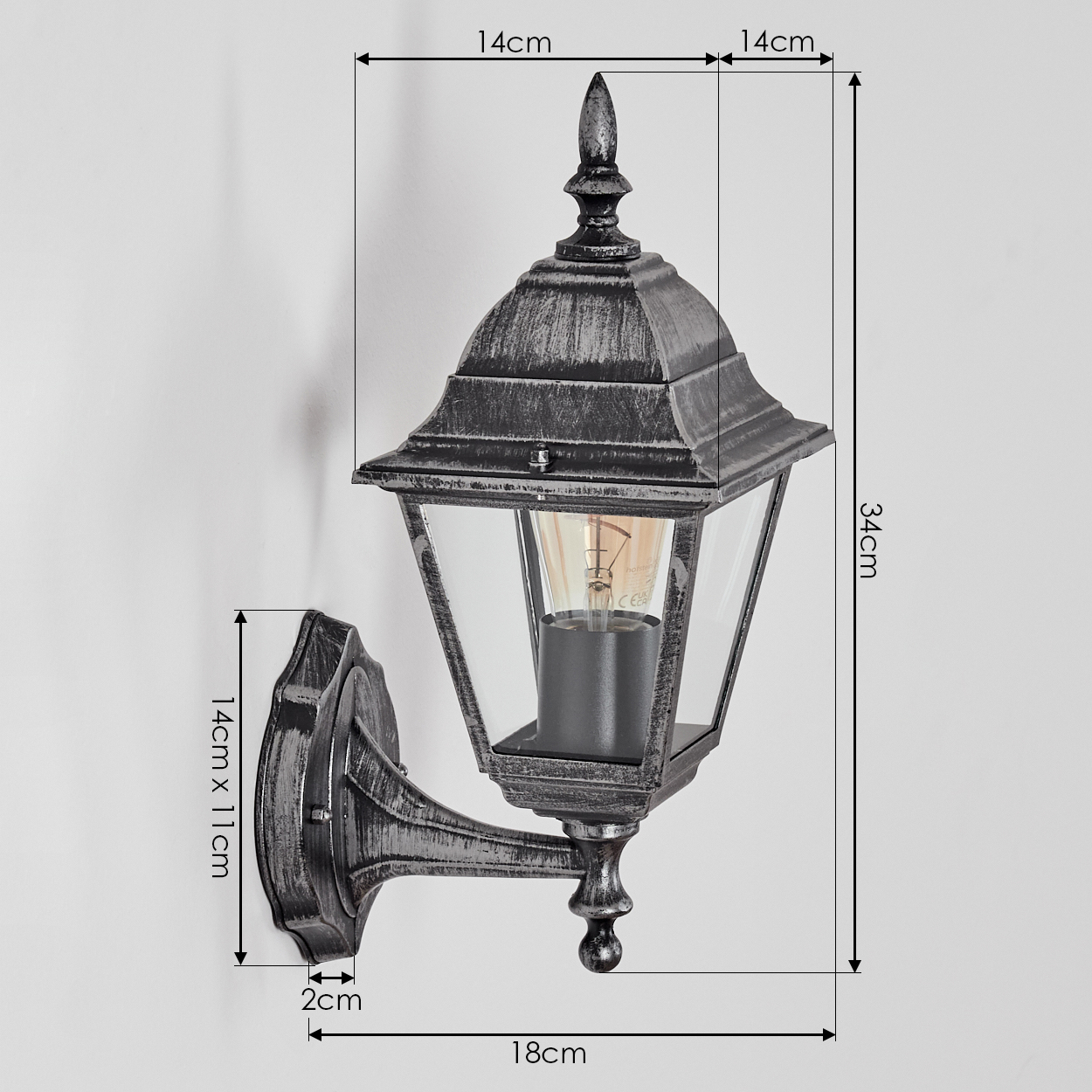 Eine dekorative Außenwandleuchte mit Maßangaben. Die Lampe ist schwarz-grau mit Glasplatten. Sie ist an einer weißen Wand montiert.