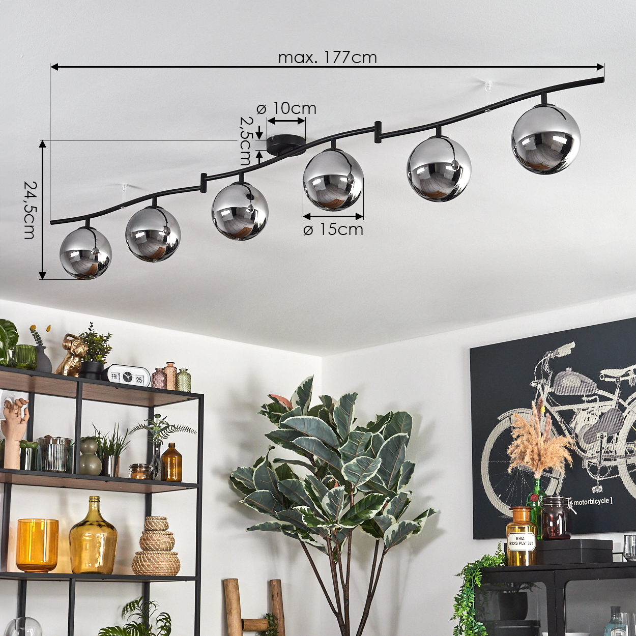 Eine moderne Deckenleuchte mit sechs verchromten kugelförmigen Lampen. Der Raum hat eine weiße Decke, Pflanzen und ein Fahrradkunstwerk.