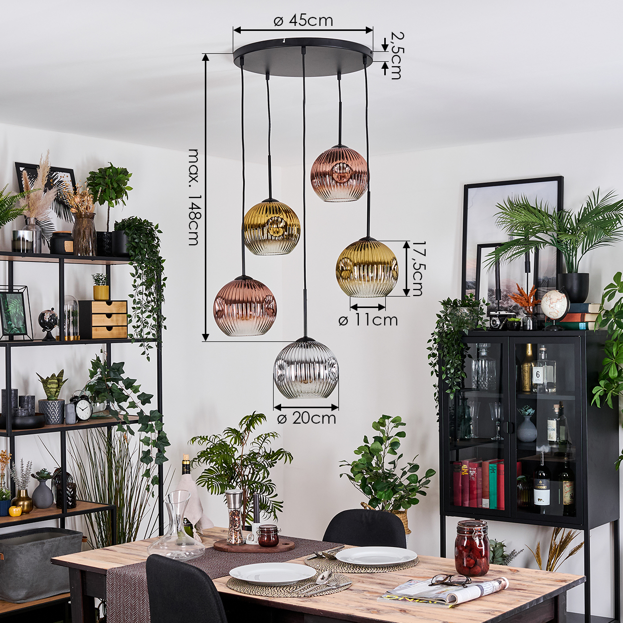 Esszimmer mit Hängelampen. Die Lampen haben Glaskugeln in verschiedenen Farben. Ein Tisch ist mit Tellern und Gläsern gedeckt.