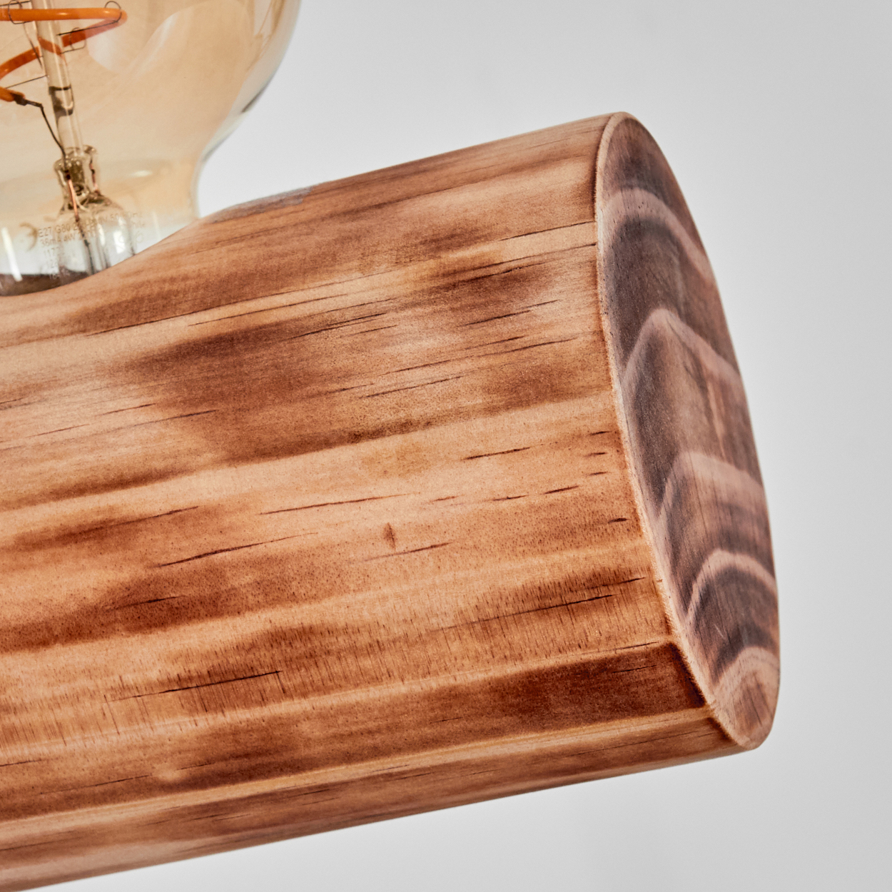 Nahaufnahme einer hölzernen Lampenhalterung mit Glühbirne. Das Holz ist braun mit sichtbarer Maserung. Der Hintergrund ist weiß.