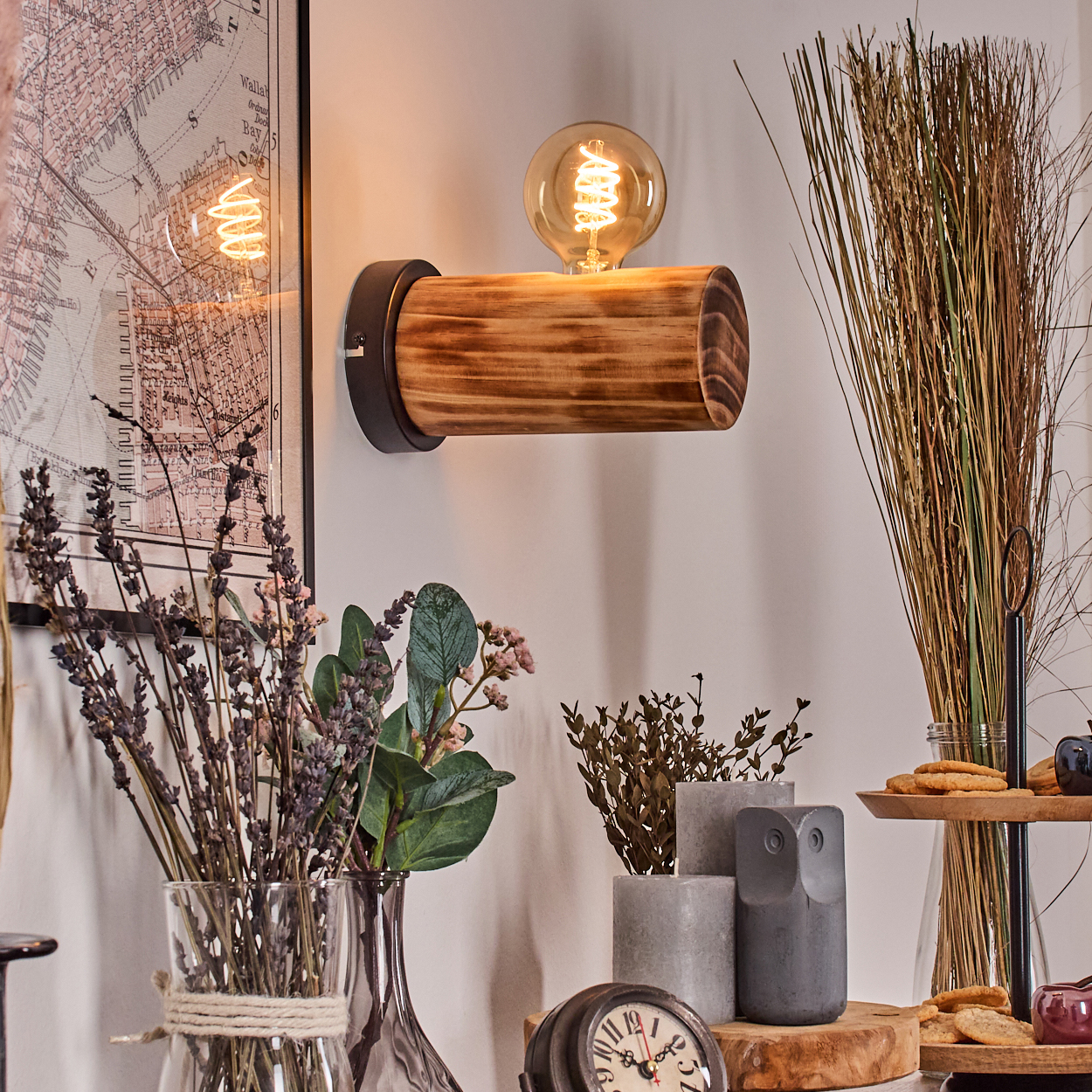 Eine rustikale Wandlampe mit Holzbalken. Trockenblumen in Vasen, eine Karte, eine Uhr und Eulendekor sind ebenfalls vorhanden.