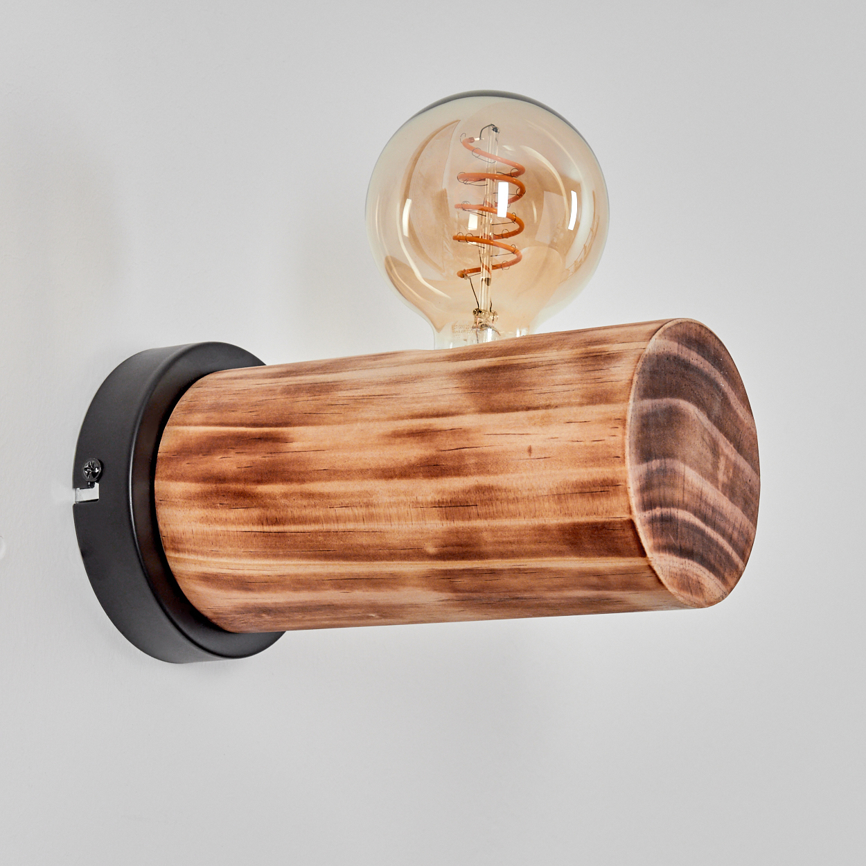 Eine hölzerne Wandlampe mit einer Glühbirne. Die Lampe hat einen zylindrischen Holzkörper und einen schwarzen Metallsockel. Der Hintergrund ist weiß.