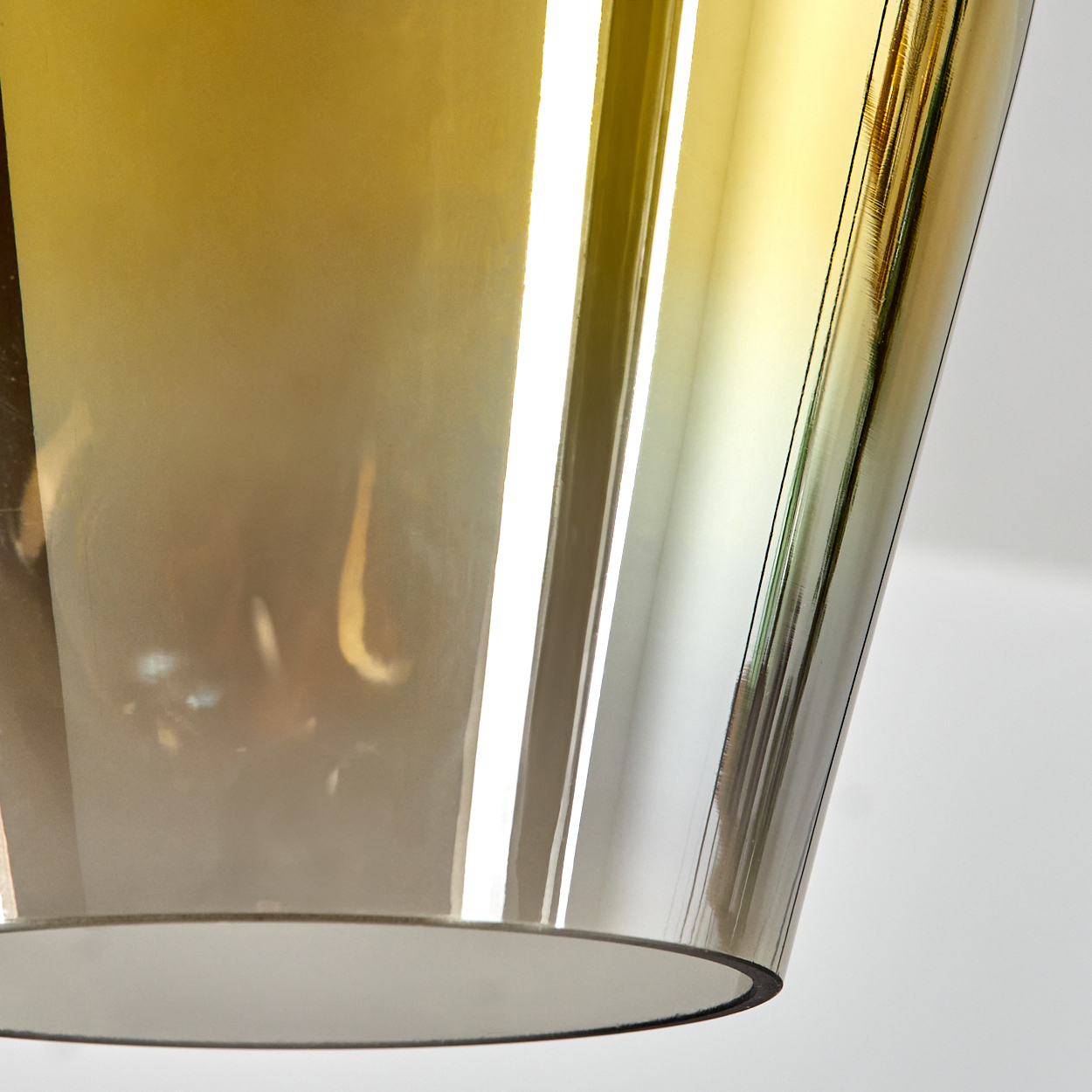 Nahaufnahme eines Lampenschirms. Er hat einen Gold- und Braunverlauf. Der Hintergrund ist weiß.