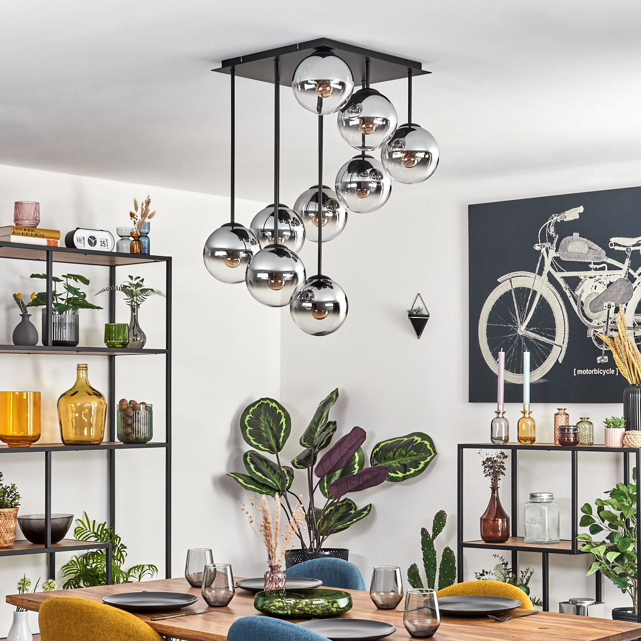 Ein Esszimmer mit Holztisch, Stühlen und Kronleuchter. Regale mit Dekorationen befinden sich auf beiden Seiten des Tisches.