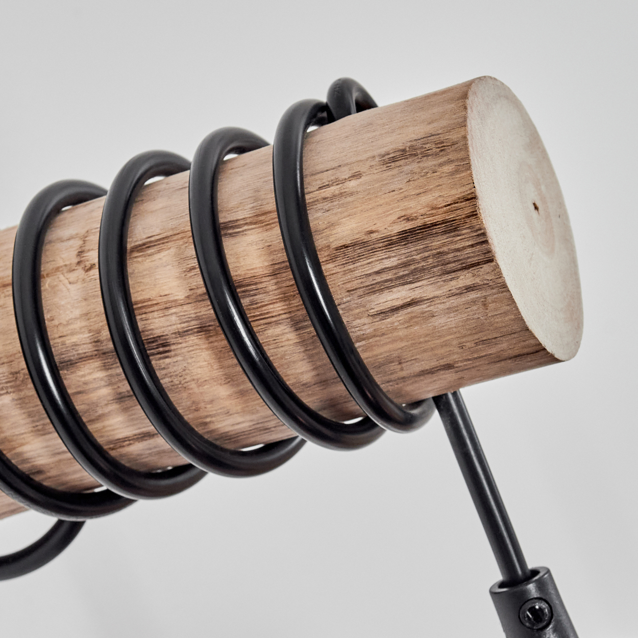 Nahaufnahme eines Holzstammes mit schwarzen Metallspulen. Der Stamm hat eine hellbraune Farbe mit sichtbarer Holzmaserung.