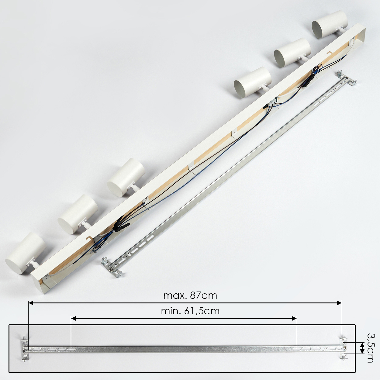 Weiße Deckenleuchte mit sechs zylindrischen Strahlern, Kabeln und Montagezubehör. Maße: max. 87 cm, min. 61,5 cm und 3,5 cm.