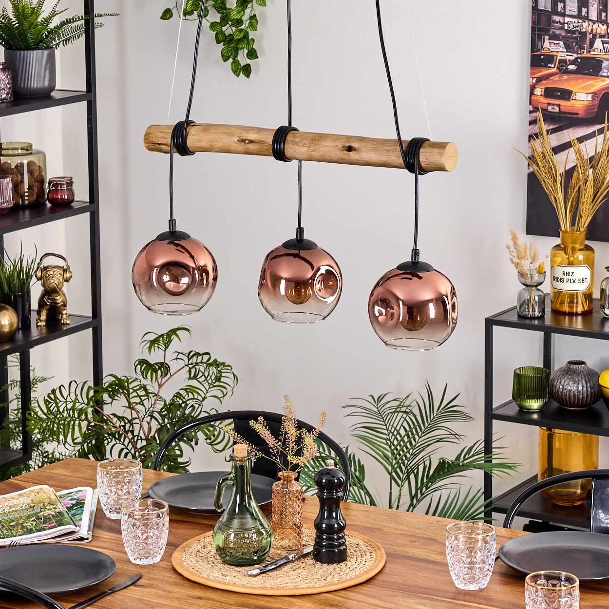 Esszimmer mit Holztisch, Kupfer-Pendelleuchten, gedecktem Tisch, Pflanzen und schwarzen Metallregalen mit Deko.