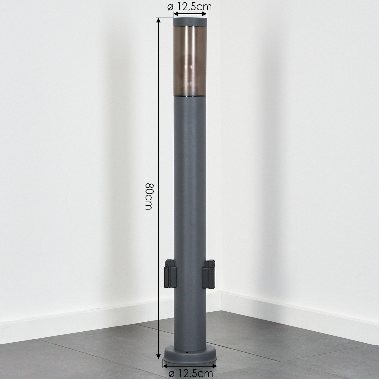 Graue Poller mit brauner Spitze, 80 cm hoch und 12,5 cm Durchmesser. Er steht auf einem grauen Fliesenboden vor einer weißen Wand.
