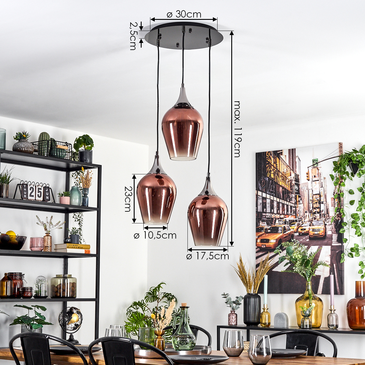 Drei kupferfarbene Pendelleuchten hängen von der Decke. Im Hintergrund ein schwarzes Regal mit Dekoration. Rechts ein Gemälde.