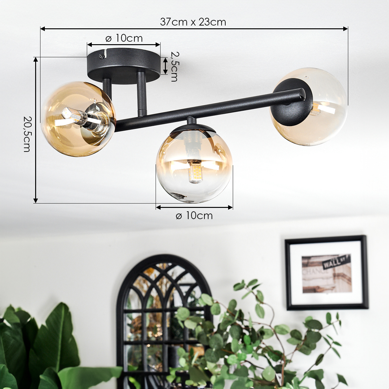 Eine moderne schwarze Deckenlampe mit drei bernsteinfarbenen Glaskugeln. Sie ist an einer weißen Decke mit angegebenen Abmessungen montiert. Der Hintergrund umfasst Dekor.