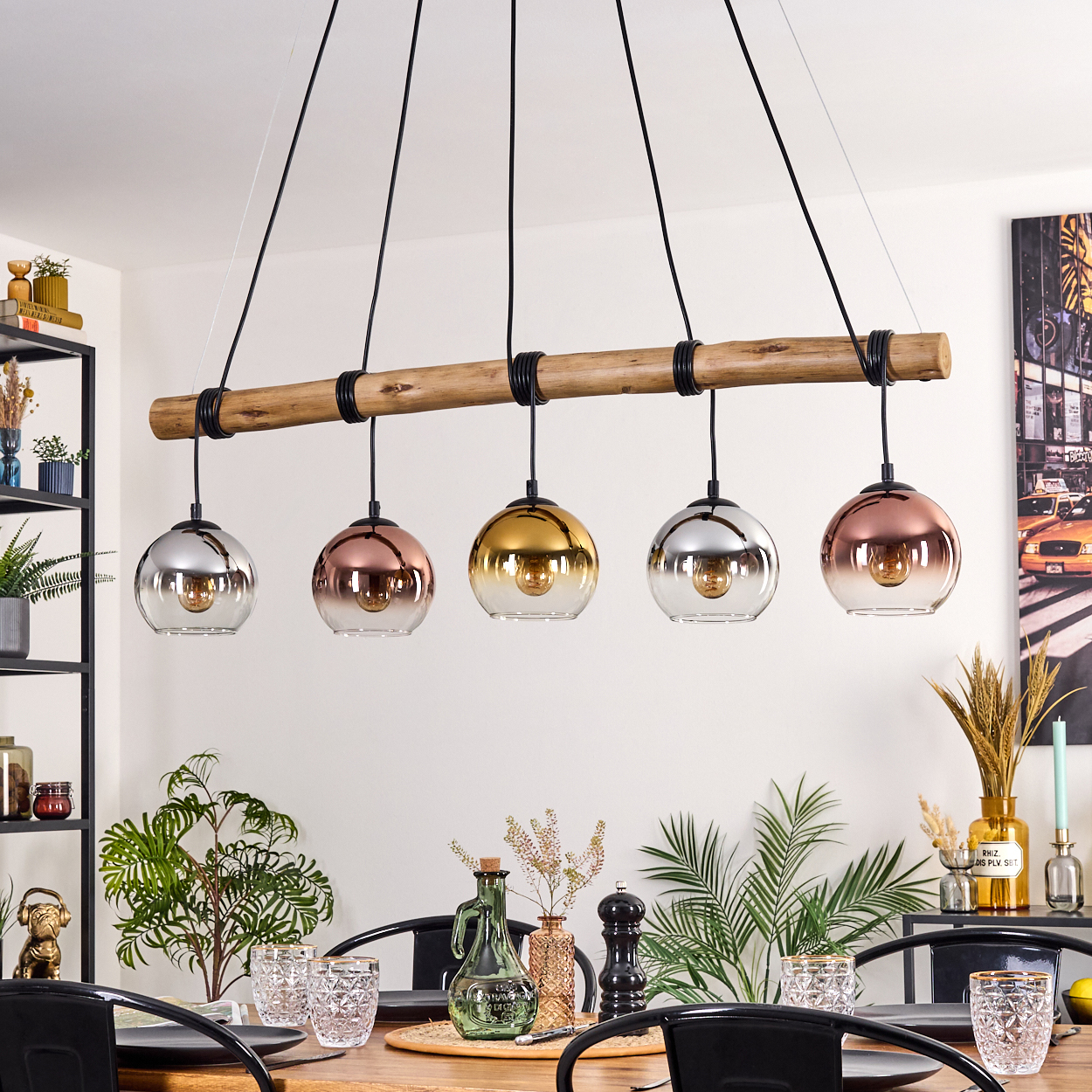 Ein Esszimmer mit Holztisch, schwarzen Stühlen und einer einzigartigen Deckenleuchte mit fünf verschiedenfarbigen Glaskugellampen.