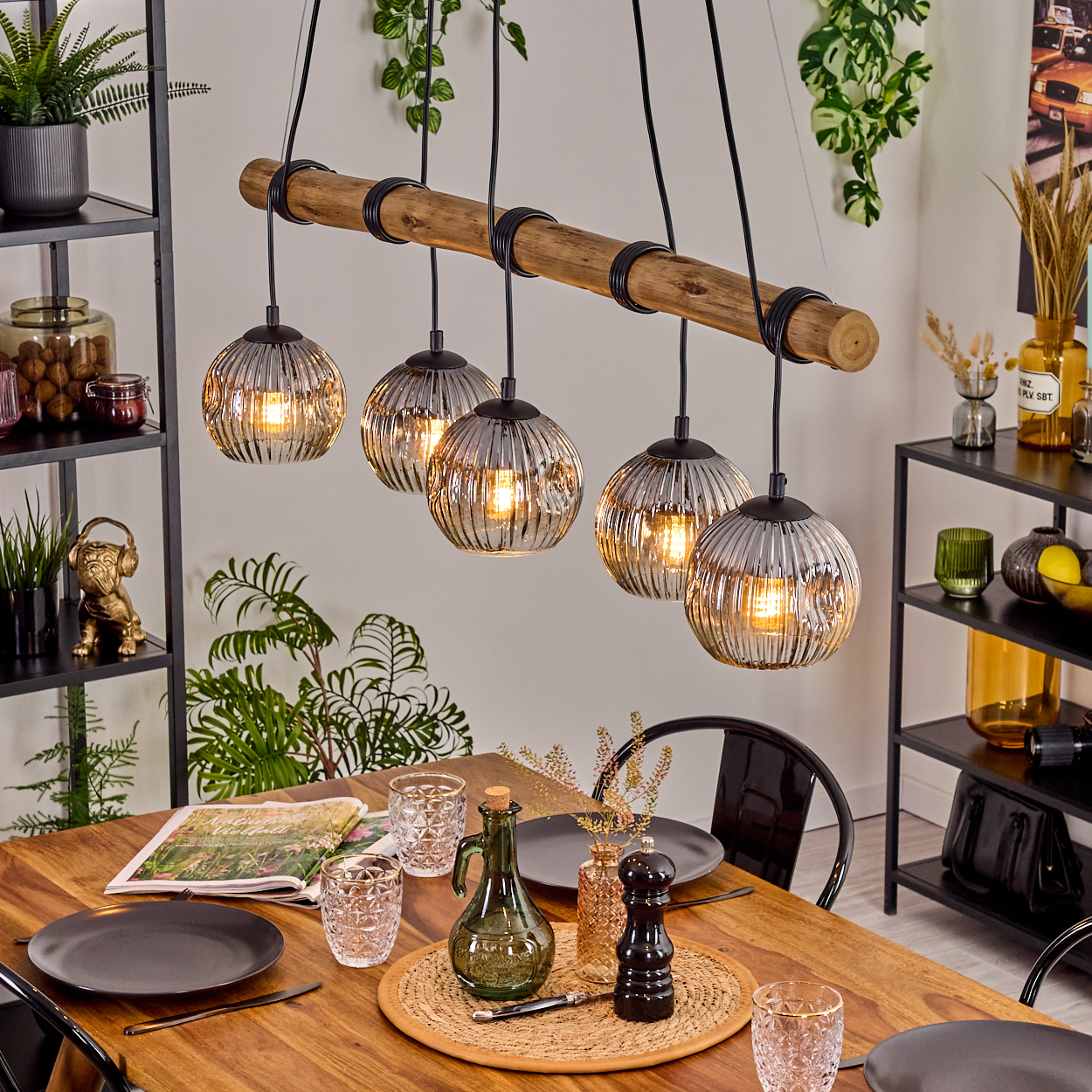 Ein Esszimmer mit Holztisch, Hängelampen und verschiedenen Dekorationselementen.