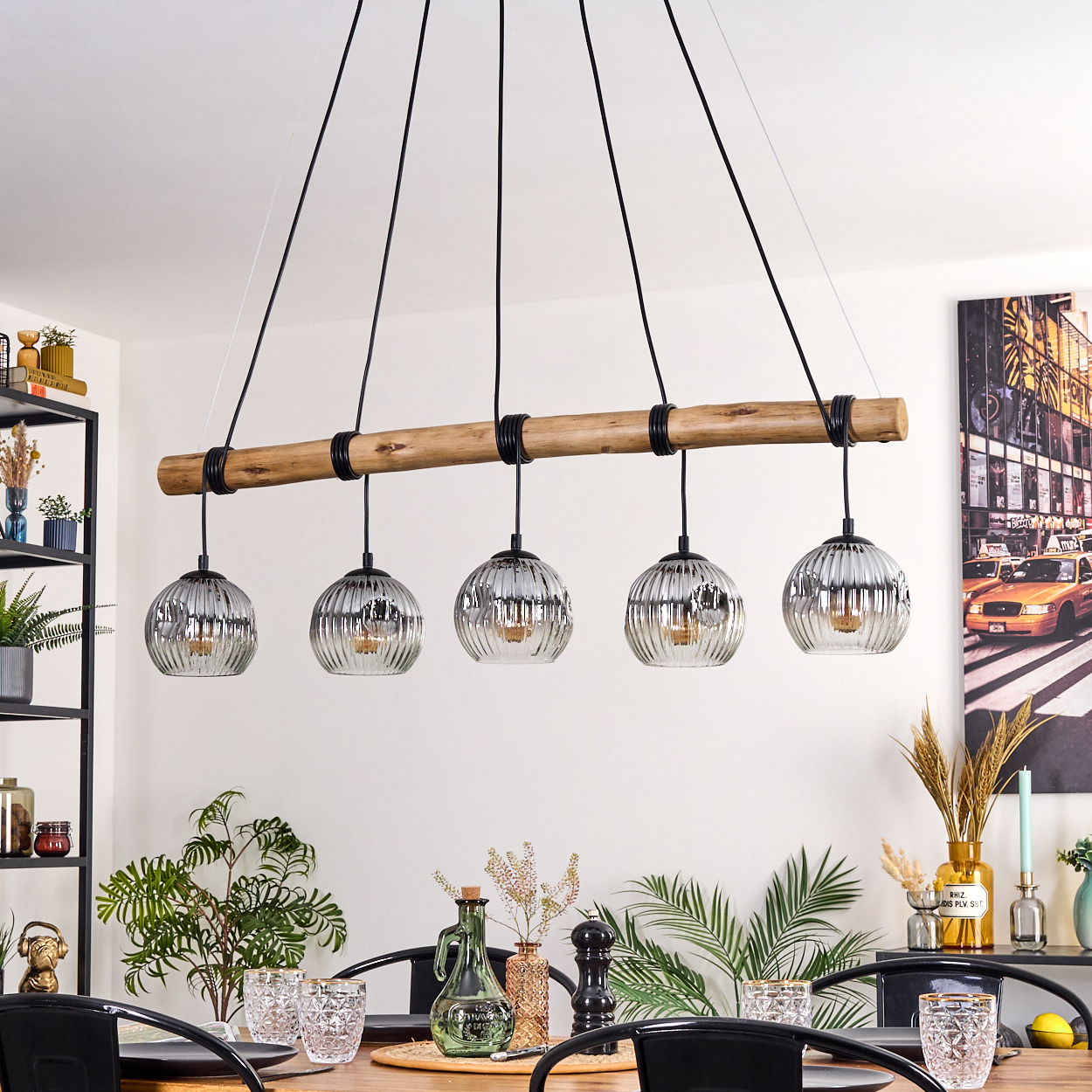 Ein Esszimmer mit Holztisch, schwarzen Stühlen und einer Hängeleuchte mit fünf Glaskugelleuchten.