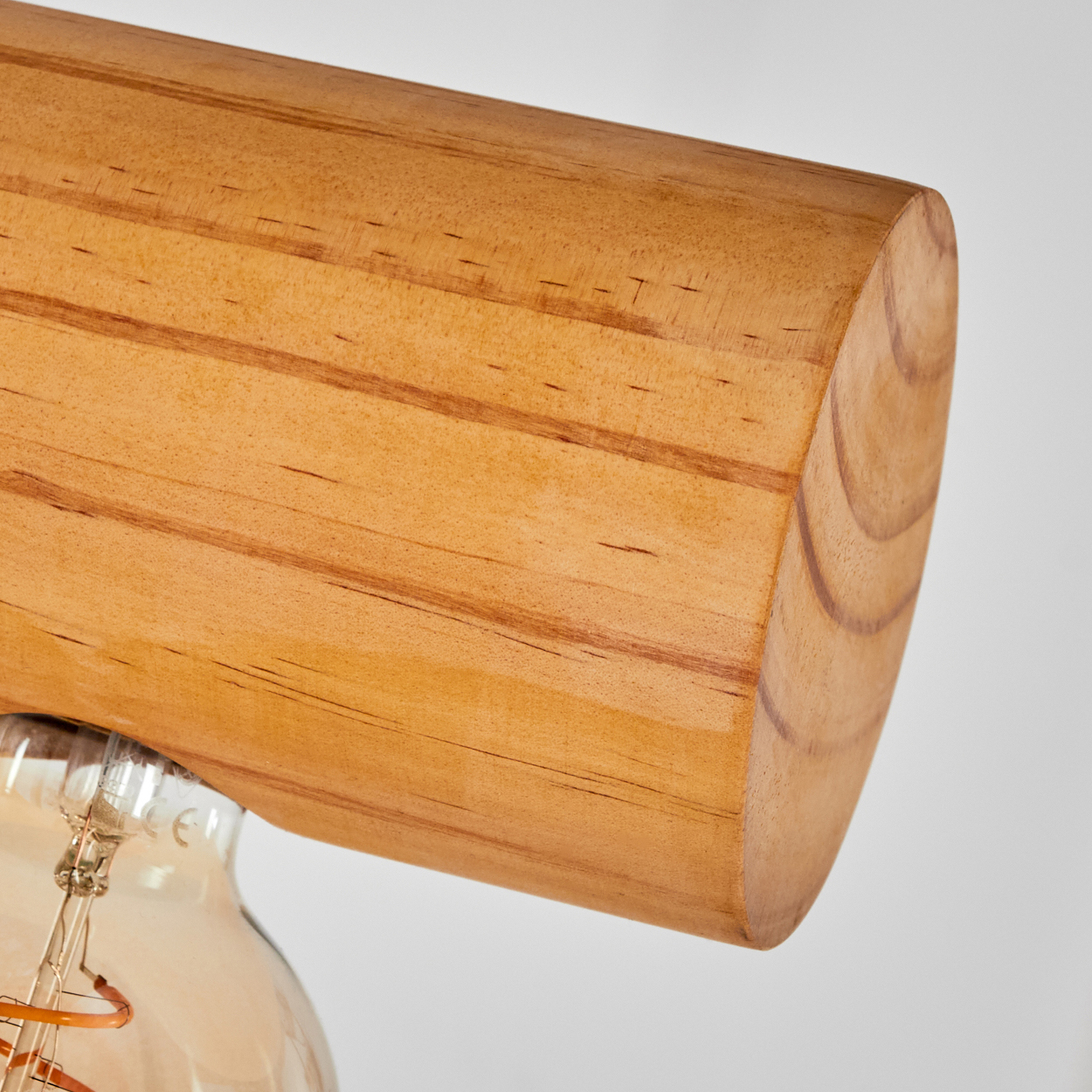 Nahaufnahme eines Holzbalkens und einer Glühbirne. Das Holz ist hellbraun mit sichtbarer Maserung. Die Glühbirne ist klar mit einem sichtbaren Glühfaden.