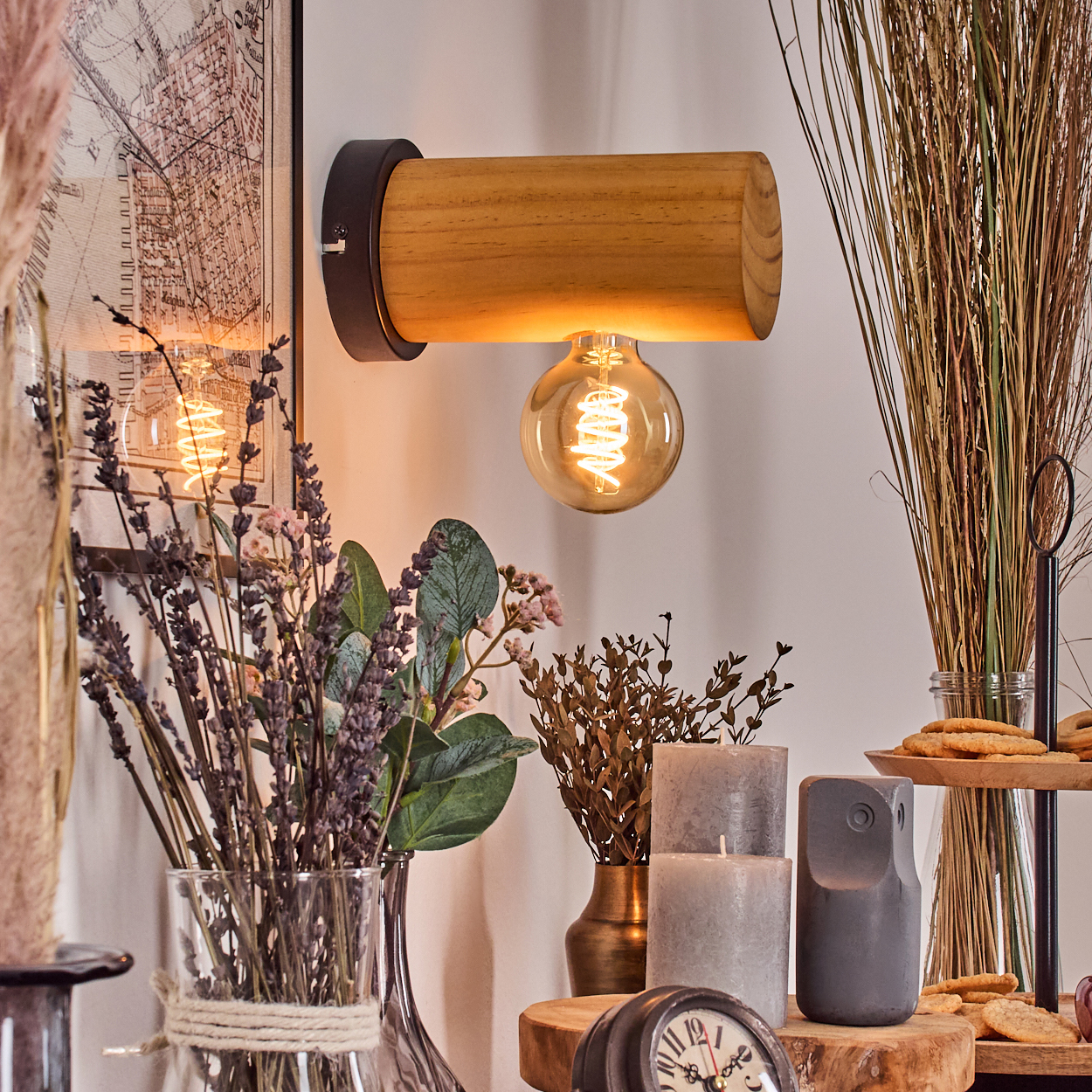 Eine hölzerne Wandlampe mit Glühbirne, umgeben von dekorativen Elementen wie Blumen, Kerzen und Keksen.