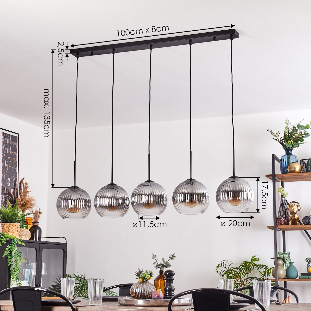 Fünf Glas-Pendelleuchten über einem Tisch. Abmessungen sind angegeben. Esstisch mit Gläsern und Dekor.
