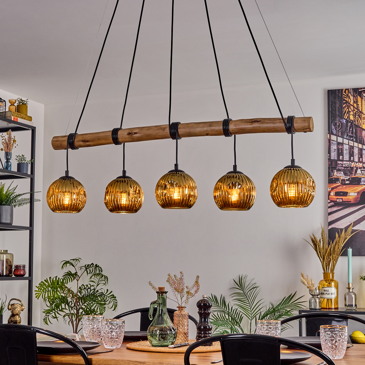 Ein Esszimmer mit Holztisch, schwarzen Stühlen und einer Leuchte mit fünf goldenen Kugellampen, die von der Decke hängen.