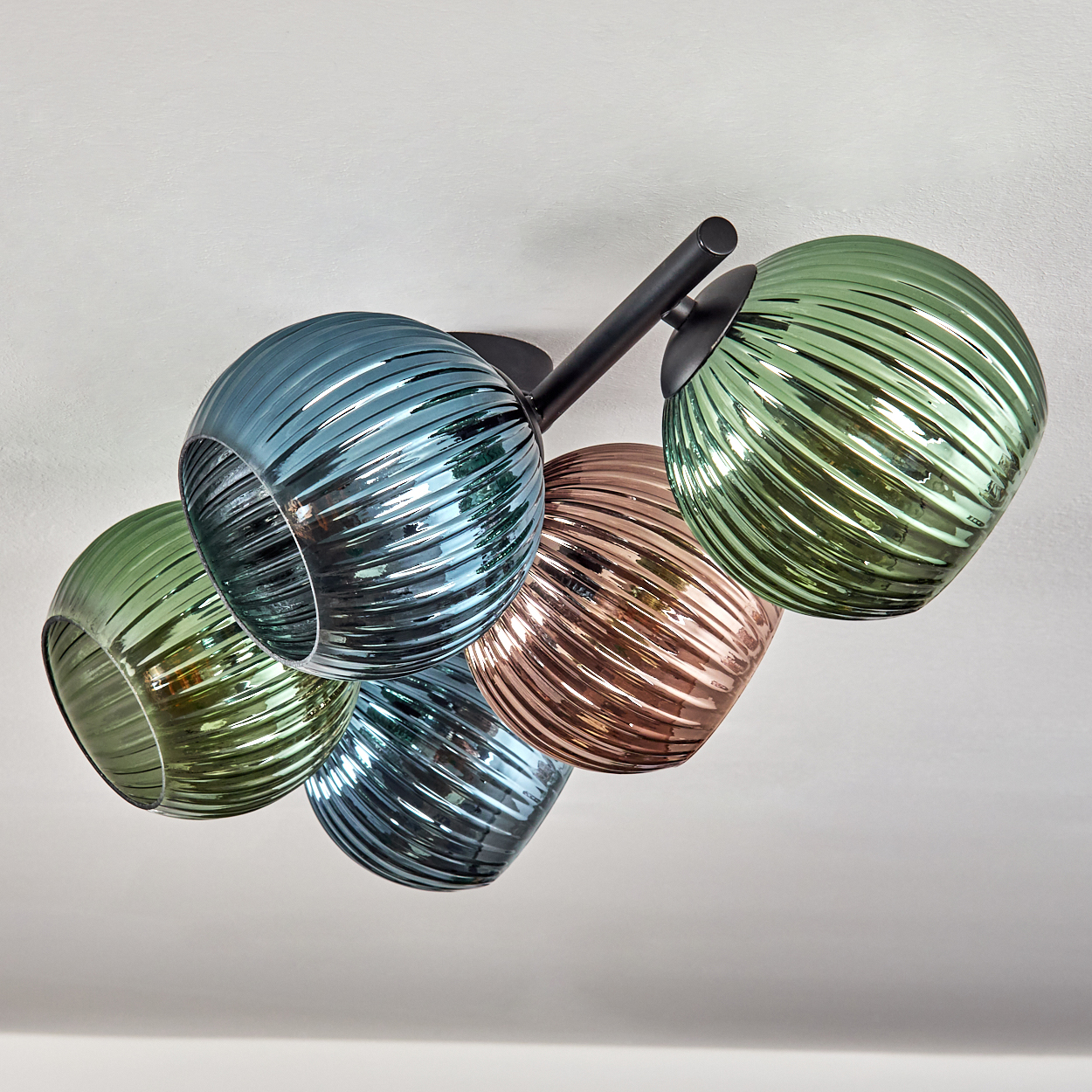 Eine moderne Deckenleuchte mit fünf kugelförmigen Glasschirmen in Blau-, Grün- und Kupferfarben, an schwarzen Metallarmen befestigt.