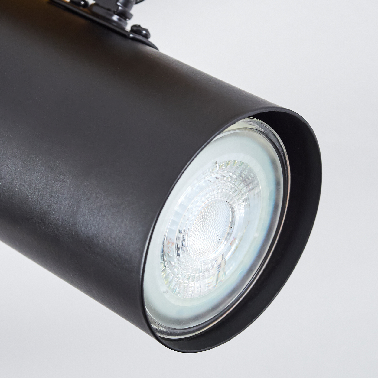 Nahaufnahme eines schwarzen zylindrischen Strahlers mit hellem LED-Licht. Der Hintergrund ist eine schlichte weiße Fläche.