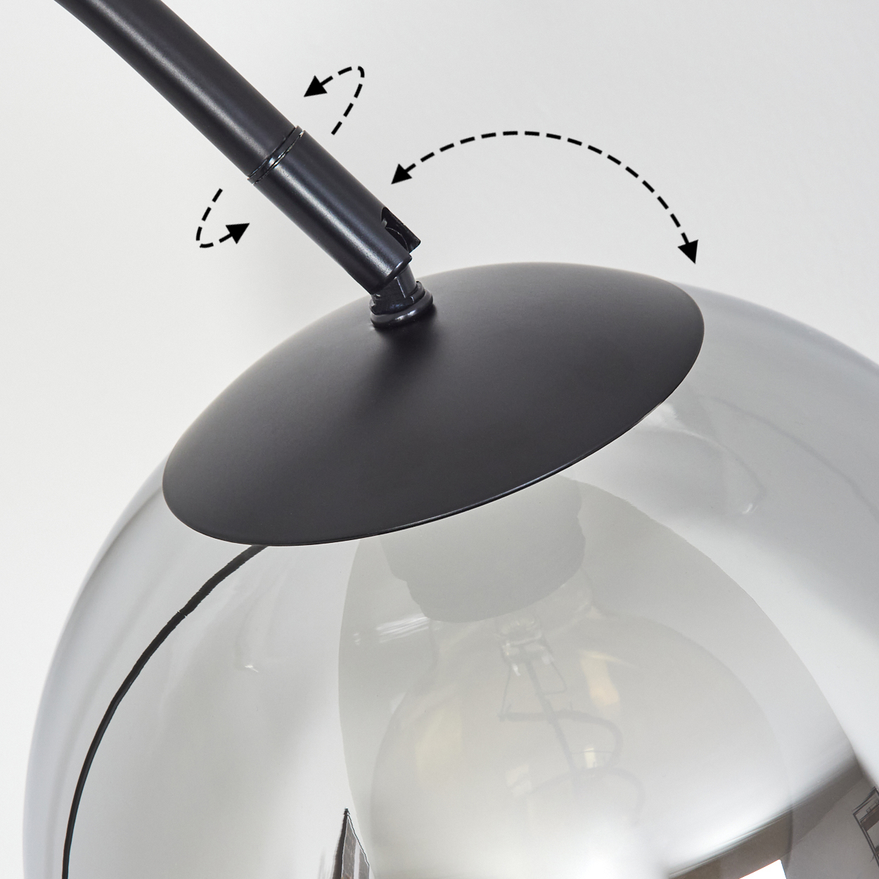 Eine moderne Lampe mit schwarzem Arm und Glasschirm. Der Schirm hat eine Kugelform. Pfeile zeigen die Bewegung des Arms an.