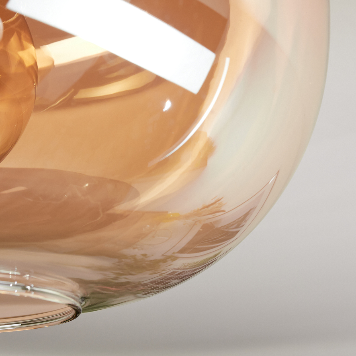 Nahaufnahme eines Glasschirms mit bernsteinfarbenen und weißen Tönen. Der Schirm hat eine runde Form und reflektiert Licht und Hintergrund.