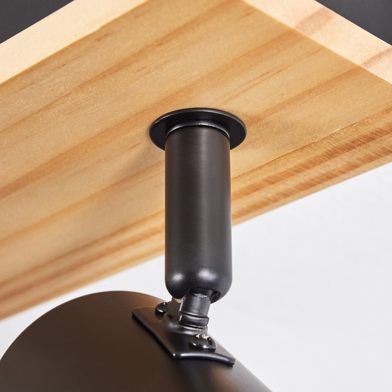 Nahaufnahme einer schwarzen Metall-Lampenhalterung, die an einem Holzregal befestigt ist. Die Halterung hat einen zylindrischen Pfosten und eine runde Lampe.