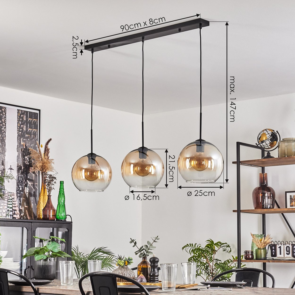 Drei Pendelleuchten mit bernsteinfarbenen Glasschirmen hängen über einem Tisch, der zum Essen gedeckt ist. Maße sind angegeben.
