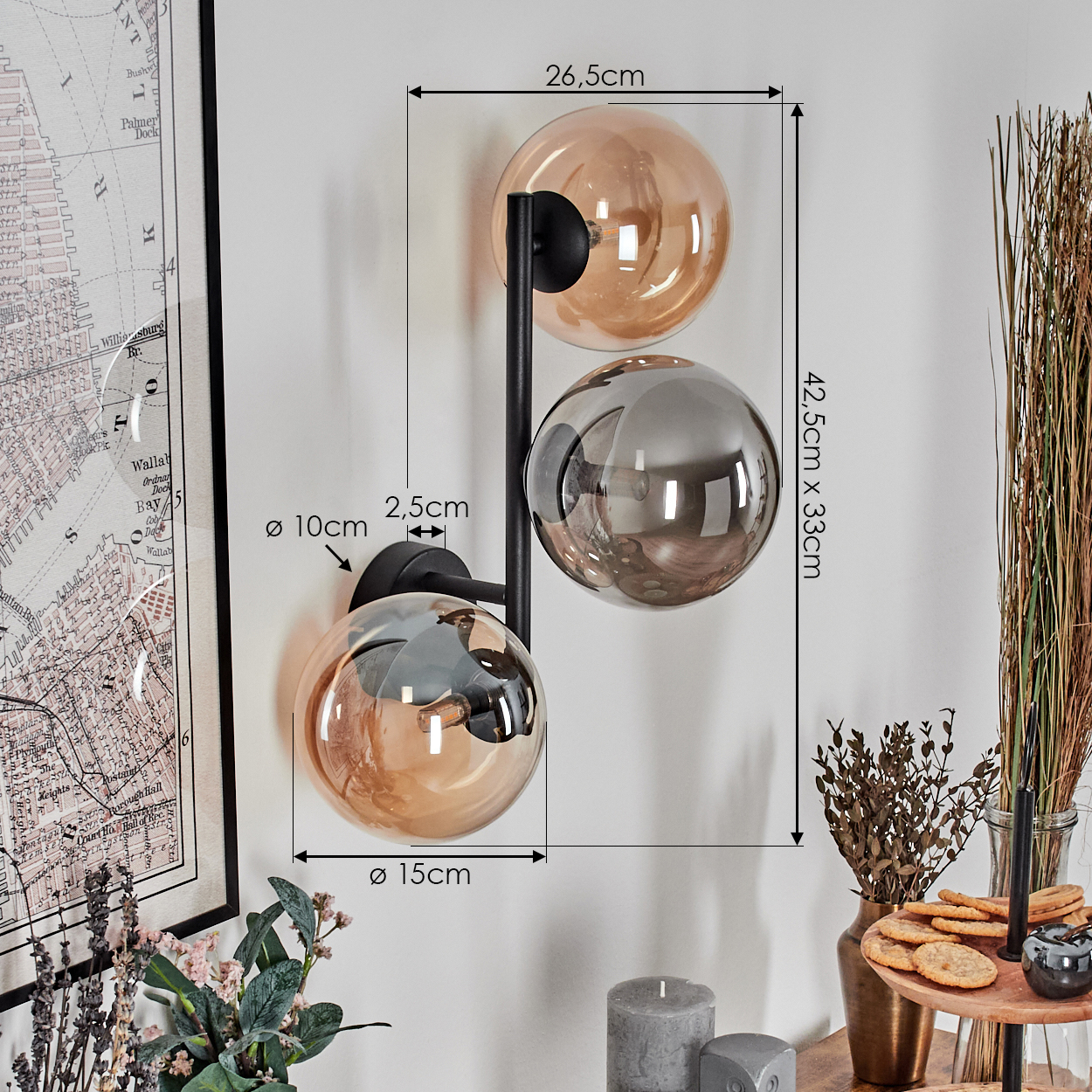 Eine Wandlampe mit drei Glaskugeln, zwei bernsteinfarben und eine graue, mit Abmessungen. Eine Karte und Dekoration befinden sich im Hintergrund.