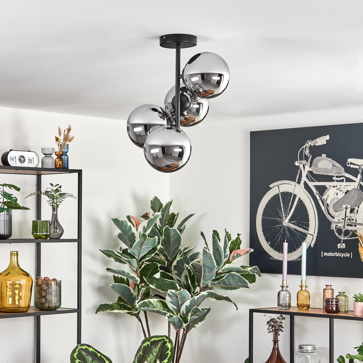 Chrom-Kugel-Kronleuchter hängt. Regale mit Vasen und Pflanzen. Kunstwerk eines Motorrads. Große, belaubte Pflanze im Vordergrund.