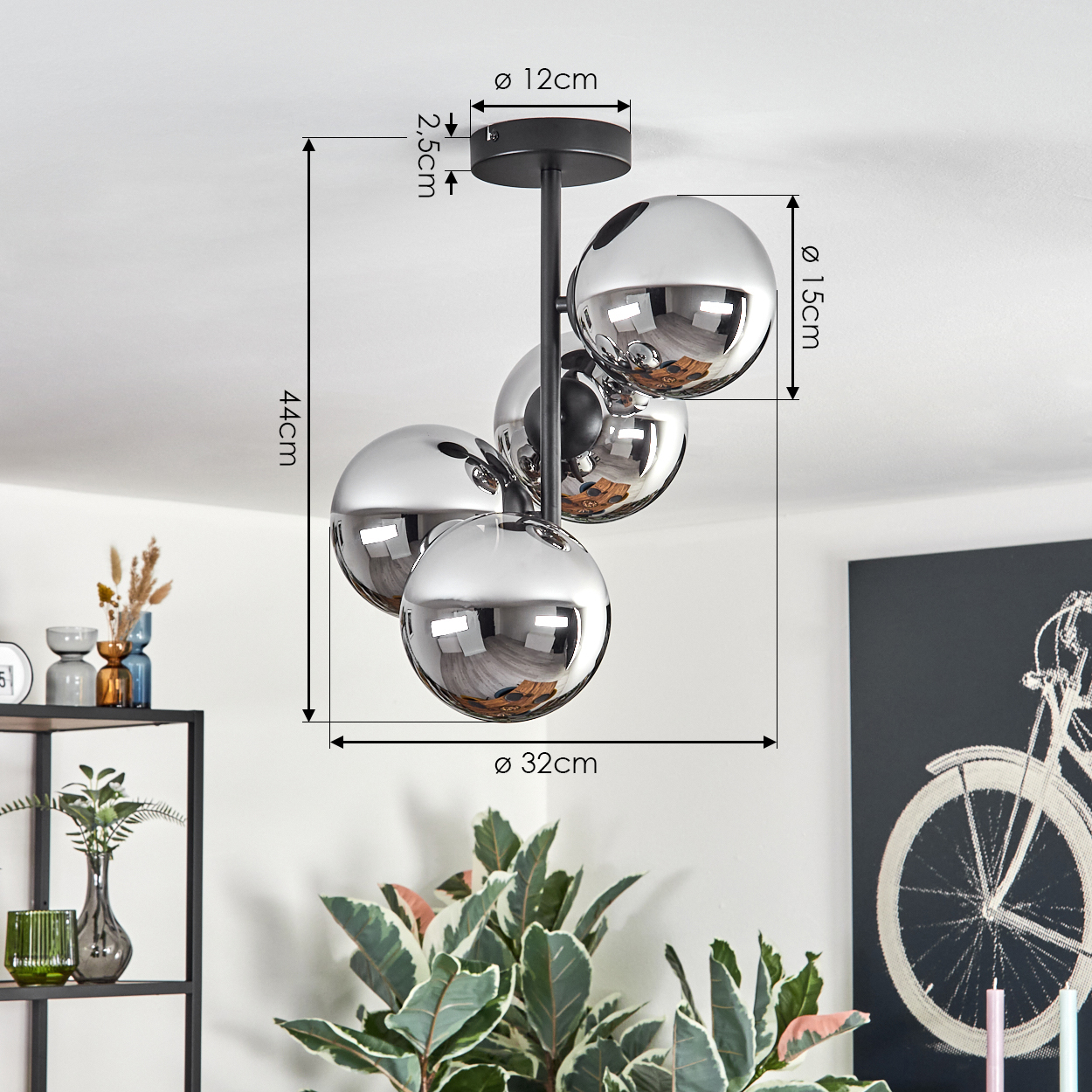 Moderne Deckenlampe mit vier Chromkugeln. Eine Pflanze und ein Fahrradgemälde befinden sich im Hintergrund. Abmessungen sind angegeben.