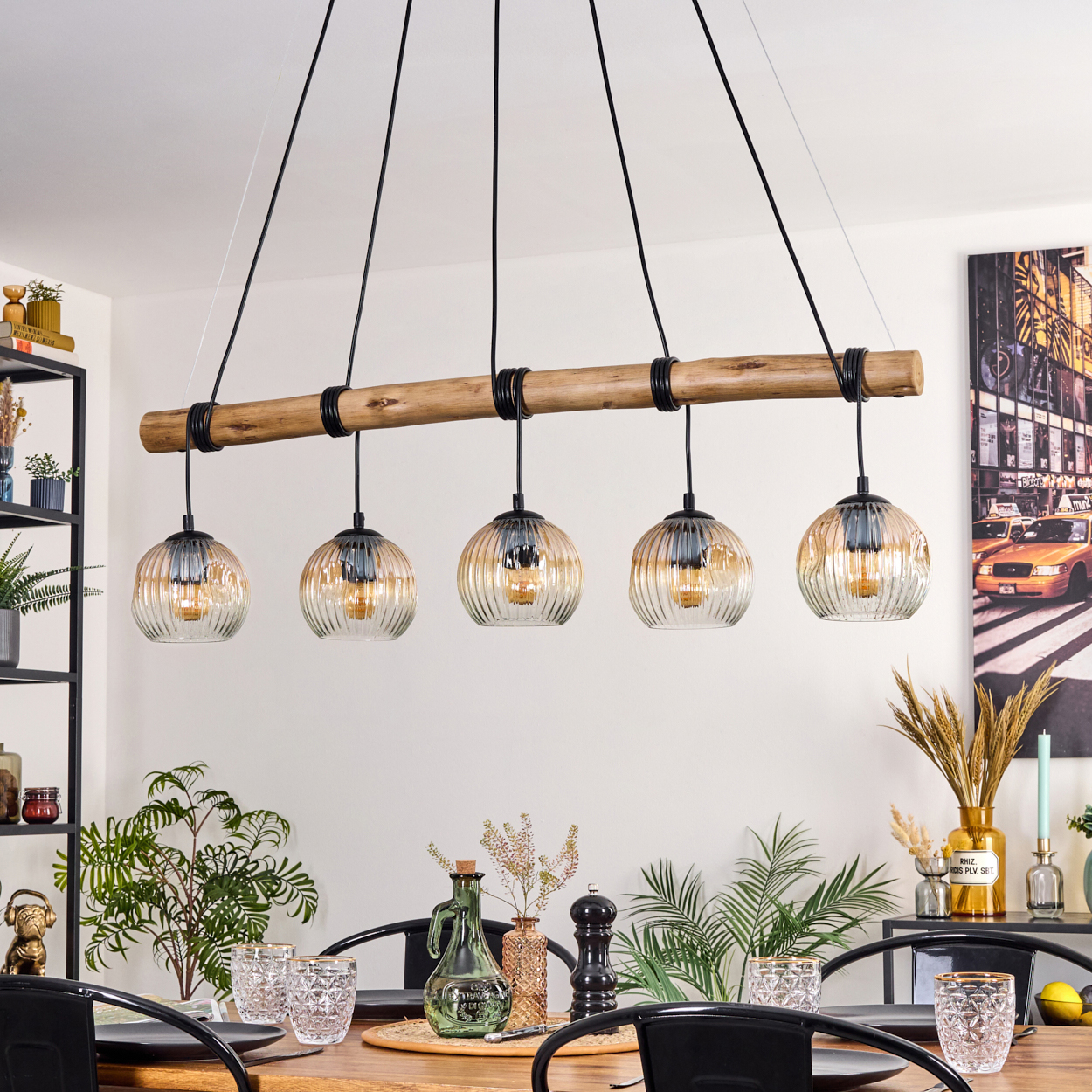 Esszimmer mit Holztisch, schwarzen Stühlen und einer Hängelampe mit fünf Glaslampen. Der Hintergrund zeigt ein NYC-Foto.