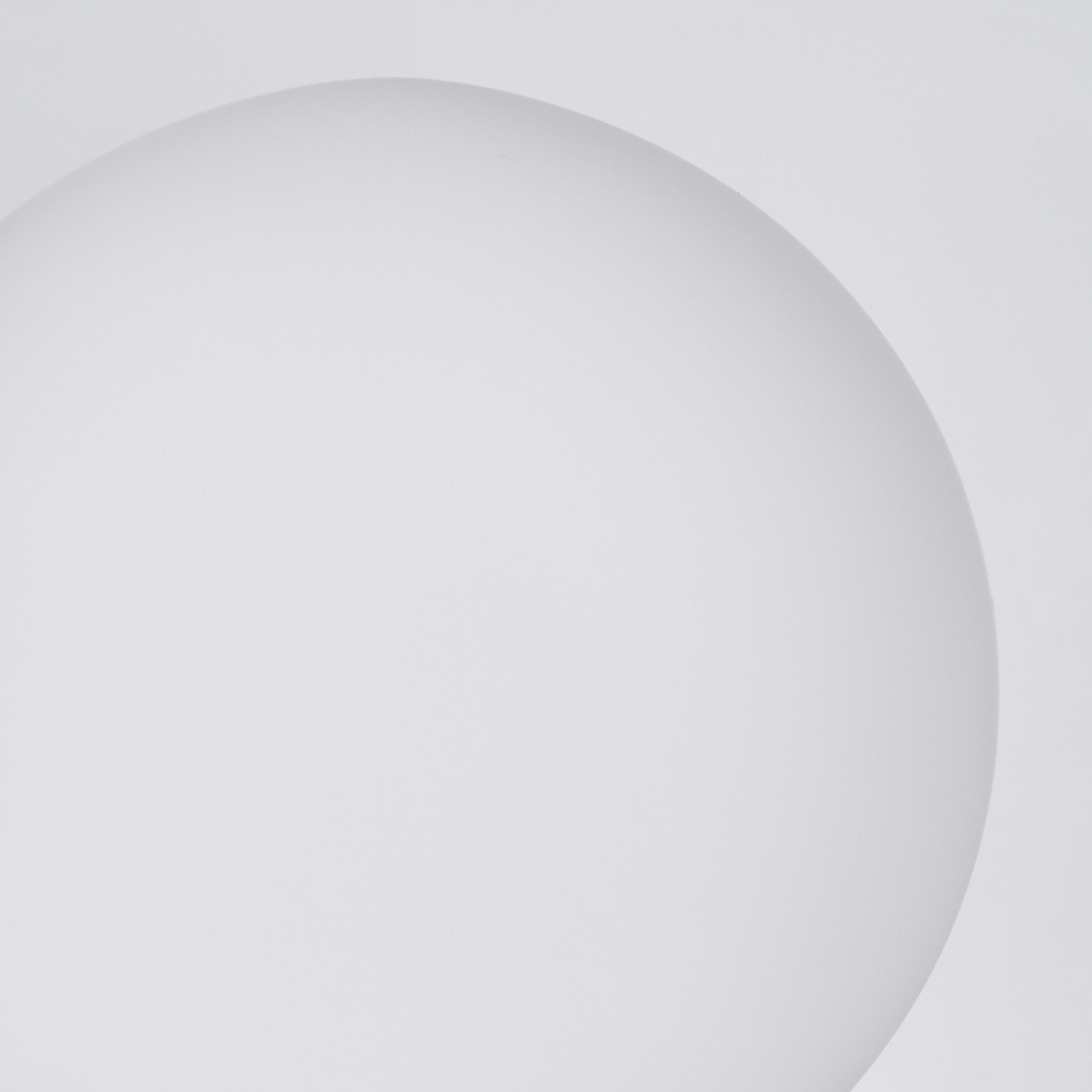 Nahaufnahme einer weißen, kugelförmigen Form vor weißem Hintergrund. Die Form ist sanft beleuchtet, wodurch sanfte Schatten entstehen.