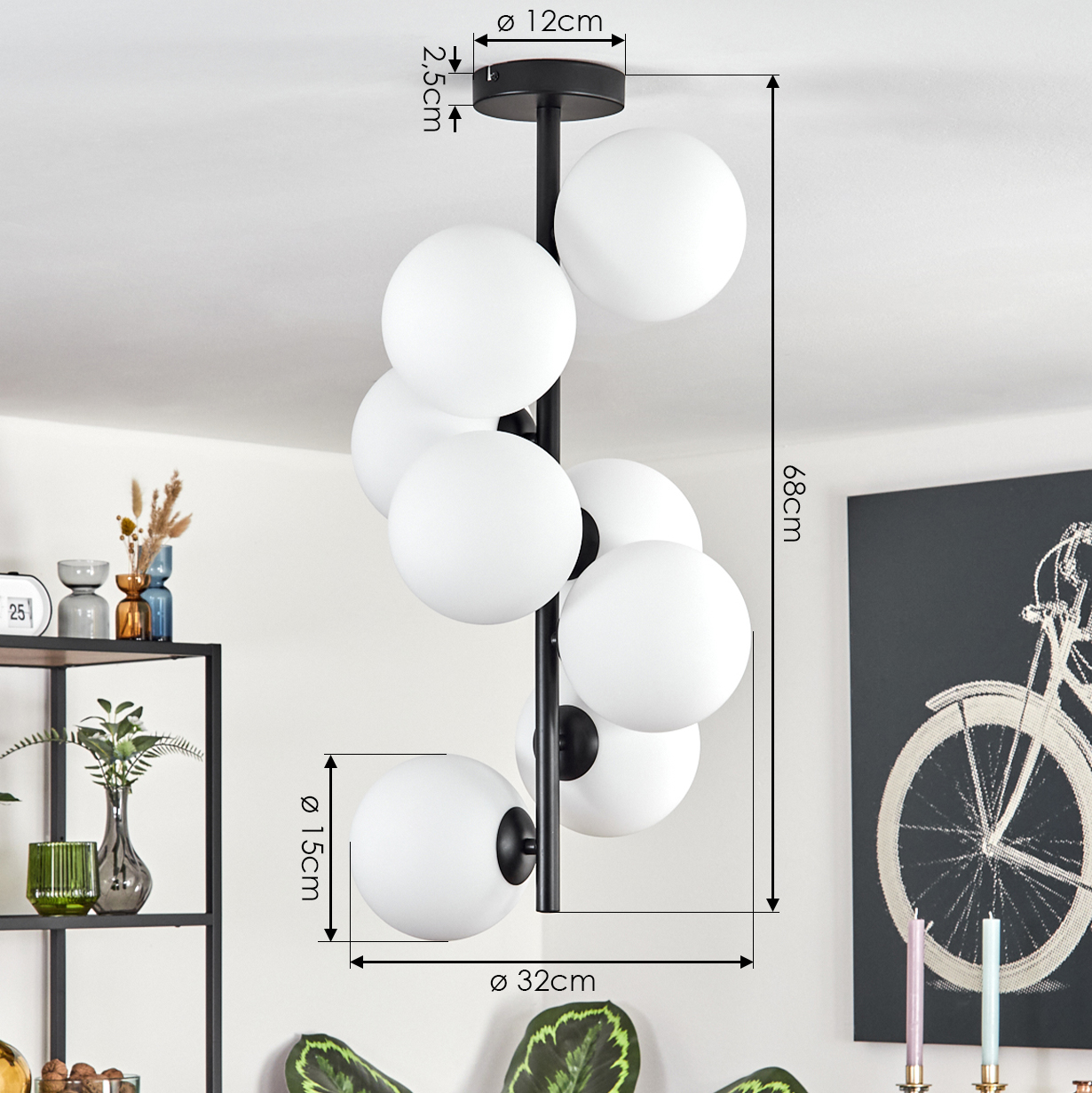 Eine moderne schwarze Pendelleuchte mit weißen Kugelleuchten. Abmessungen sind angegeben. Im Hintergrund befindet sich ein Regal mit Dekoration.