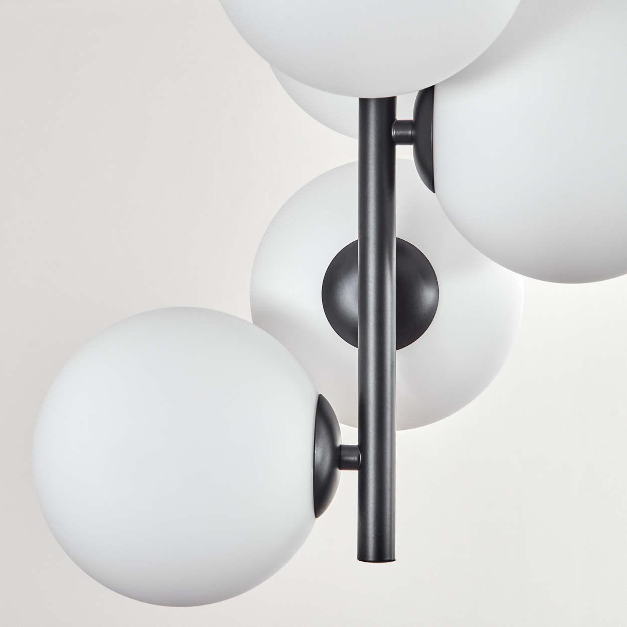 Eine moderne Lampe mit weißen Kugelleuchten und einem schwarzen Metallrahmen vor weißem Hintergrund.