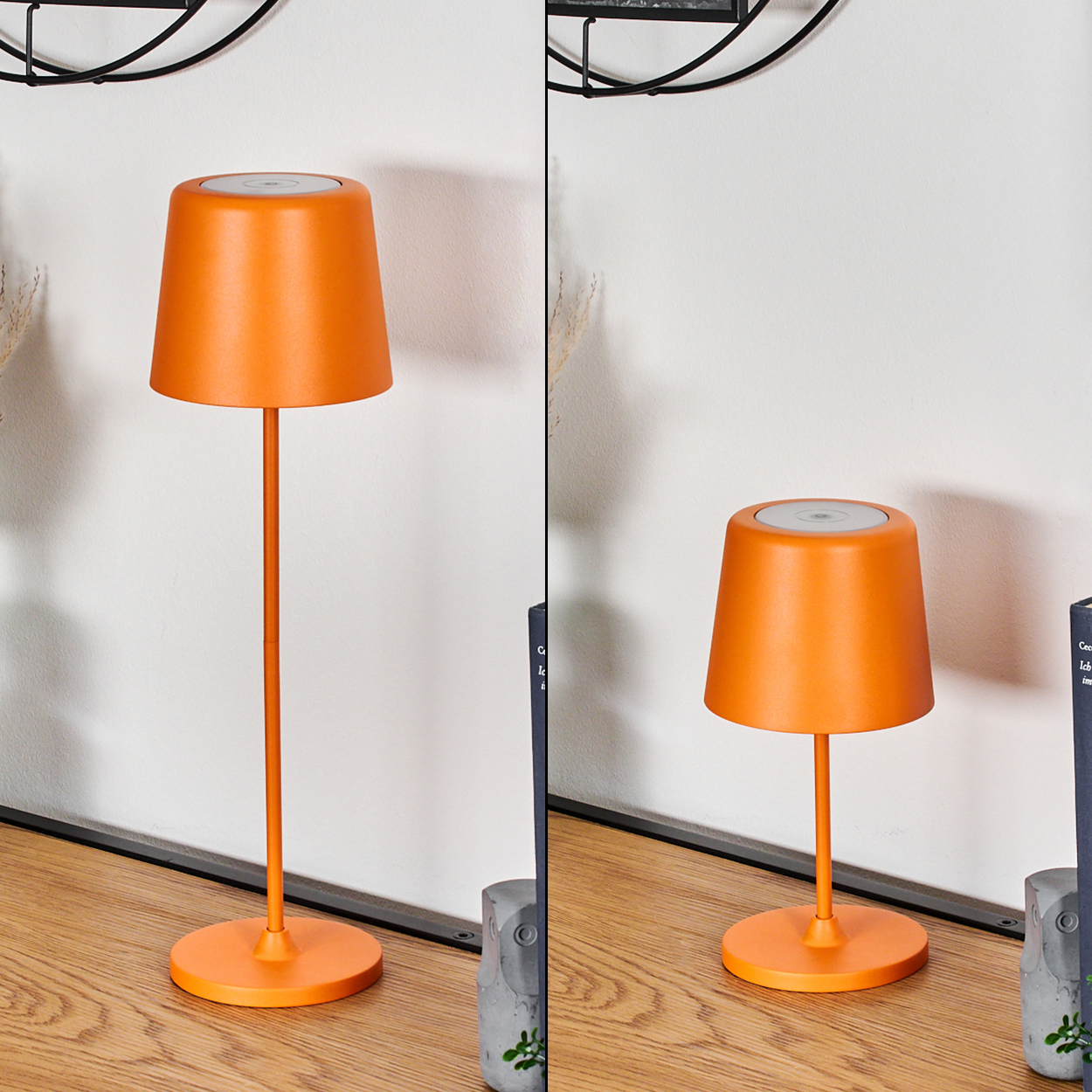 Zwei orangefarbene Lampen mit weißen Oberteilen stehen auf einer Holzoberfläche. Eine weiße Wand und ein schwarzes Dekorationselement im Hintergrund.