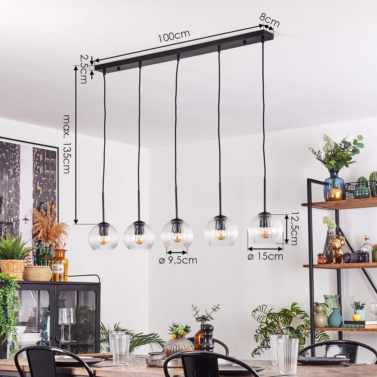 Ein Esszimmer mit einer Pendelleuchte. Die Leuchte hat fünf klare, gerippte Glaskugeln, die über einem Holztisch hängen.