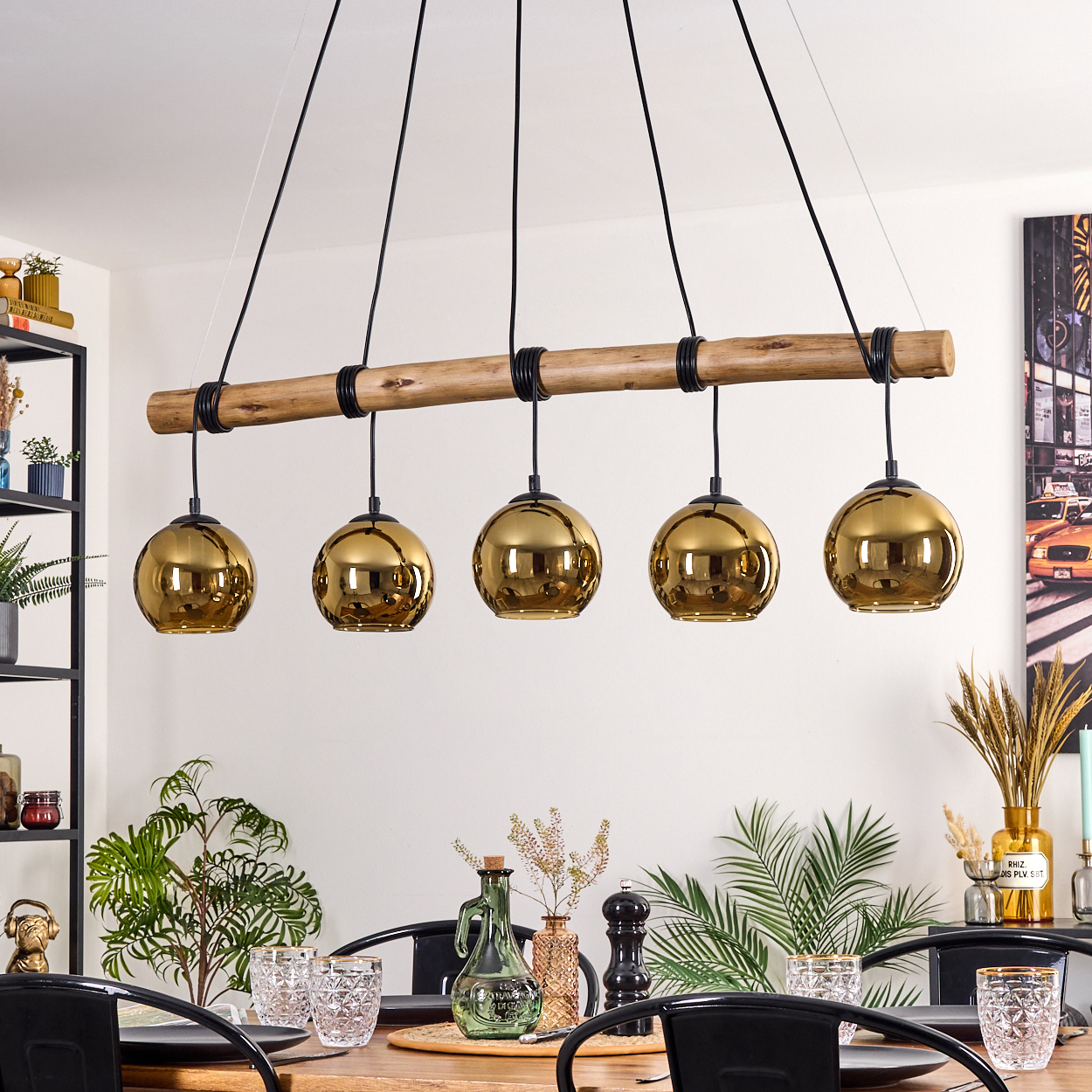 Ein Esszimmer mit Holztisch, schwarzen Stühlen und einer Hängeleuchte mit fünf goldenen Kugellampen.