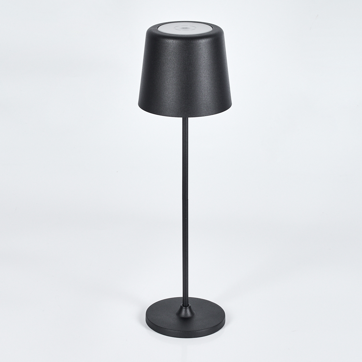 Eine schwarze Lampe mit konischem Schirm, dünnem Stiel und rundem Fuß. Sie befindet sich vor einem schlichten weißen Hintergrund.