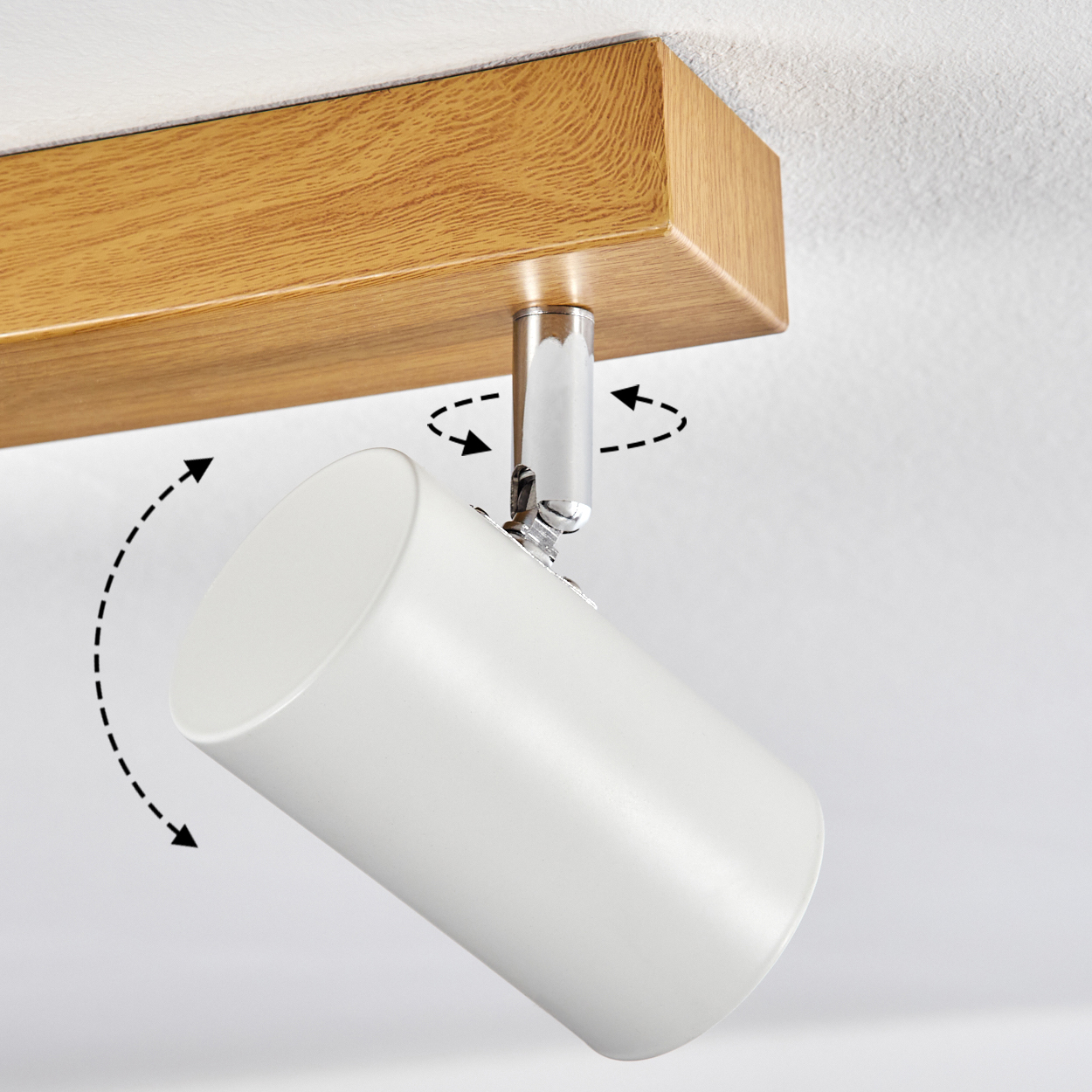 Ein weißer zylindrischer Strahler ist an einem Holzbalken montiert. Pfeile zeigen die einstellbaren Winkel des Lichts. Der Hintergrund ist eine weiße Decke.