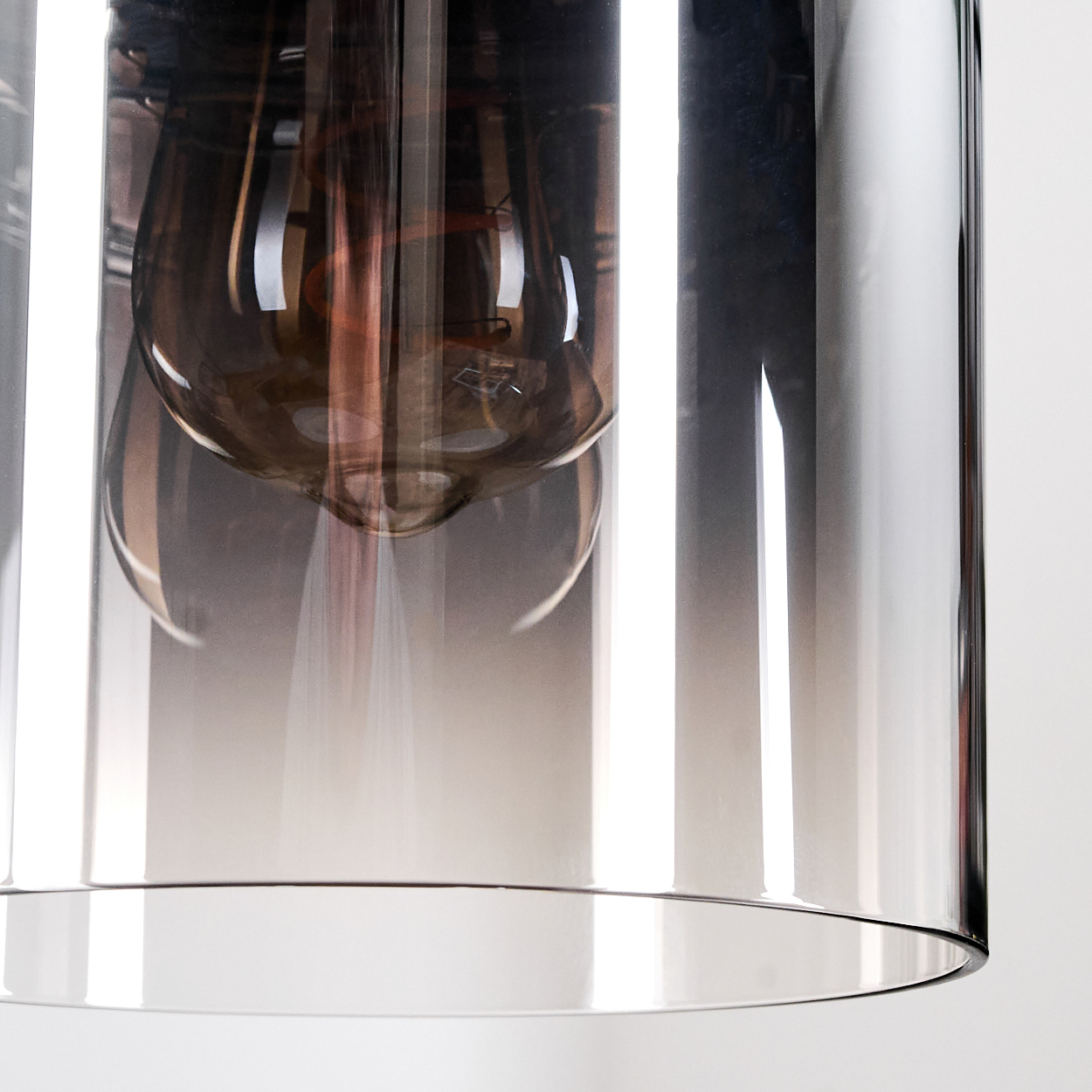 Nahaufnahme einer Glasleuchte mit einer Glühbirne im Inneren. Das Glas ist klar und rauchig mit weißem Hintergrund.