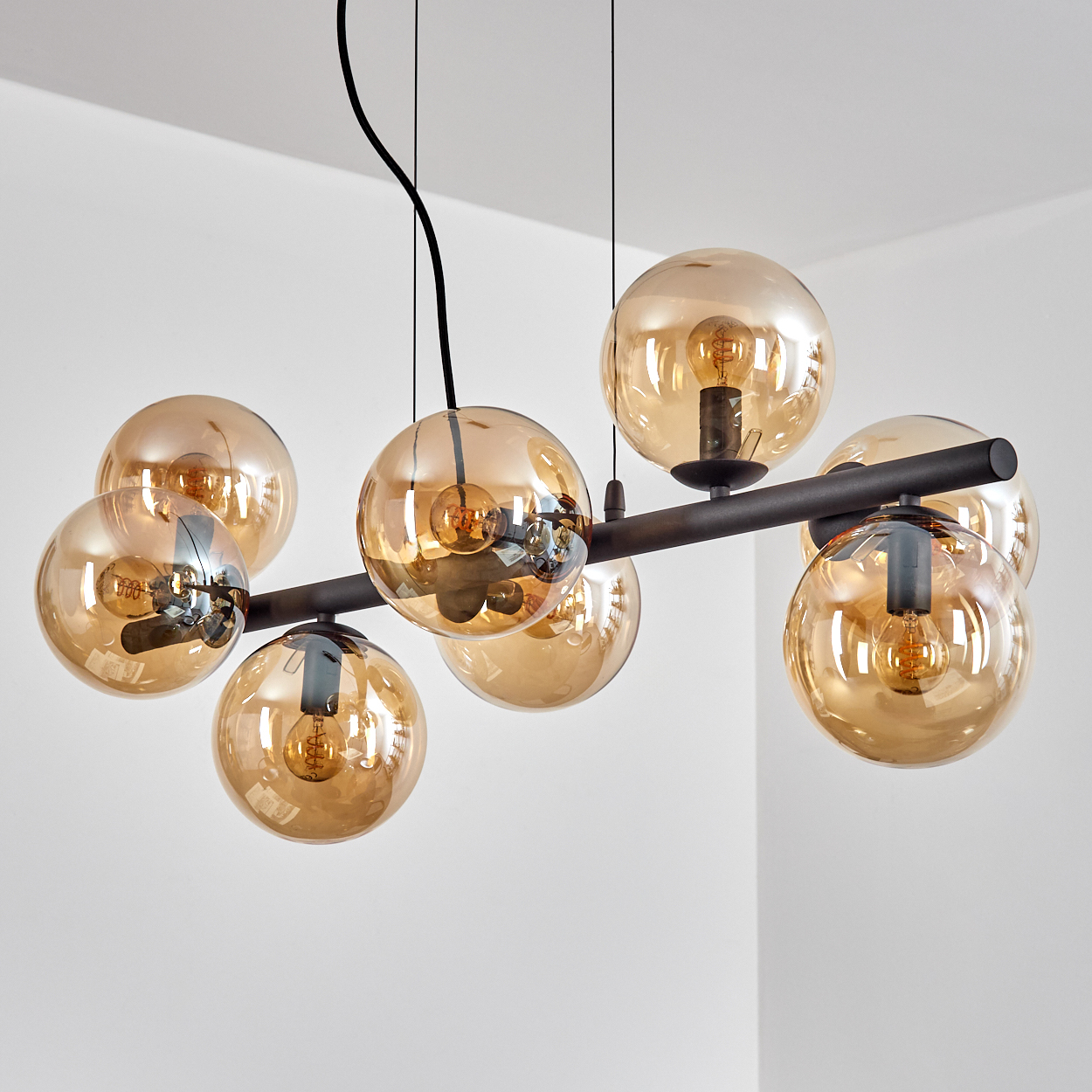 Eine moderne Deckenleuchte mit acht bernsteinfarbenen Glaskugeln, jede mit einer Glühbirne, an einem schwarzen Metallrahmen.
