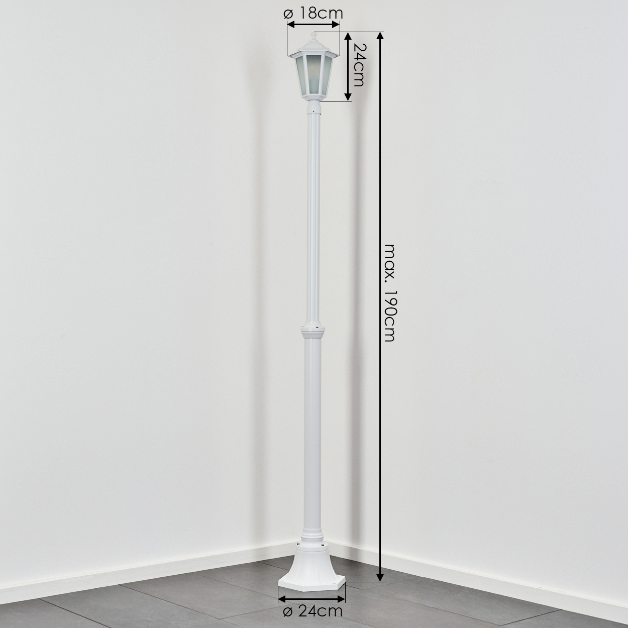 Eine weiße Außenlaterne steht vor einer weißen Wand. Abmessungen: 18 cm, 24 cm und max. 190 cm. Sockel ø 24 cm.
